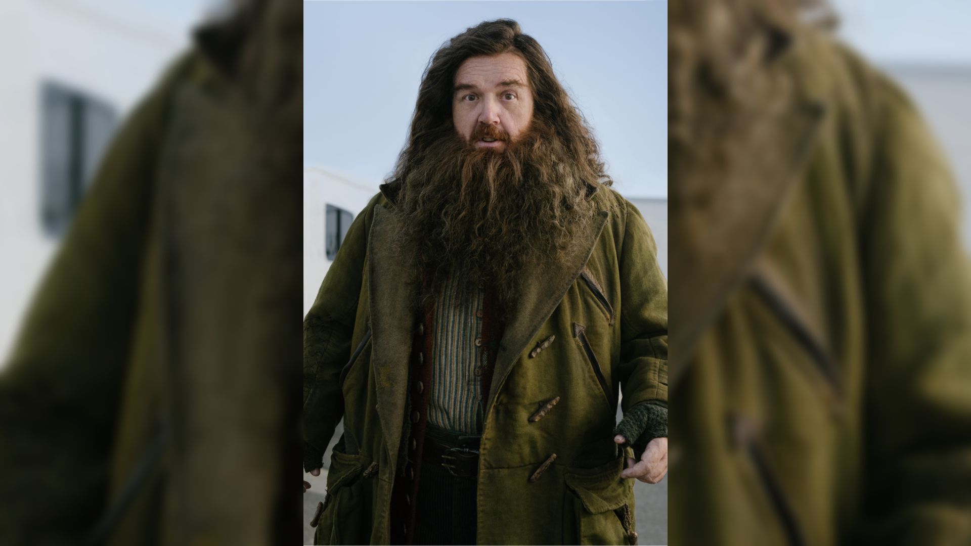 L'attore Nick Frost in un cappotto verde con una lunga barba e capelli lunghi