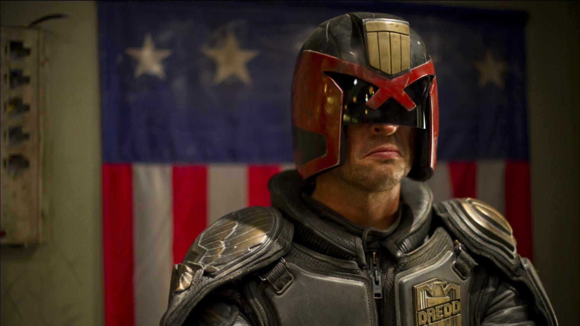 L'attore Karl Urban in tuta grigia futuristica ed elmo nero-rosso