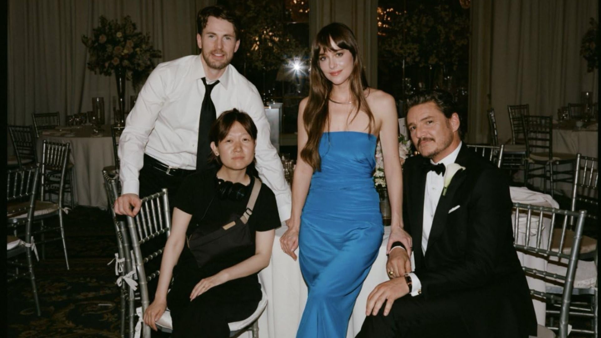 Gli attori Dakota Johnson, Chris Evans e Pedro Pascal seduti in abiti da sera a un tavolo bianco
