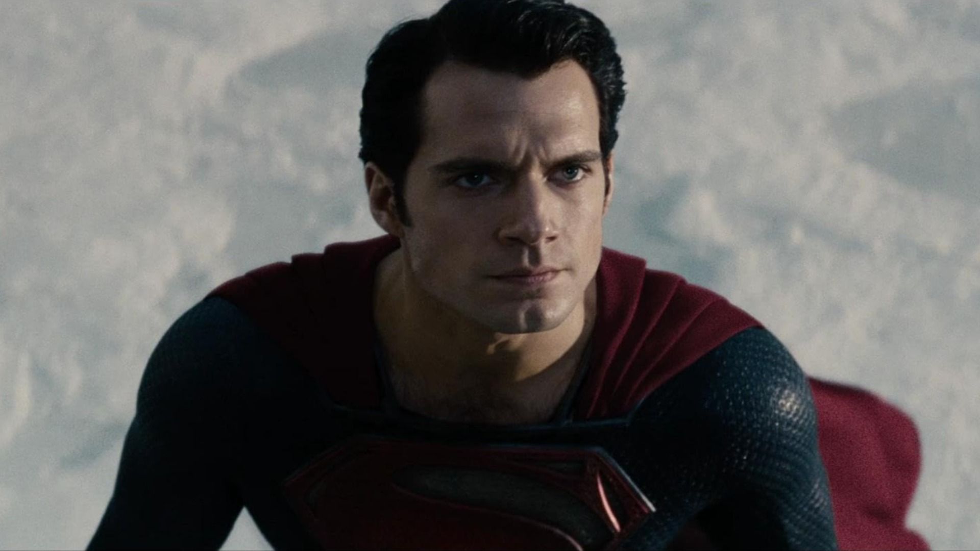 L'attore Henry Cavill in costume da supereroe blu e rosso con la lettera S sul petto