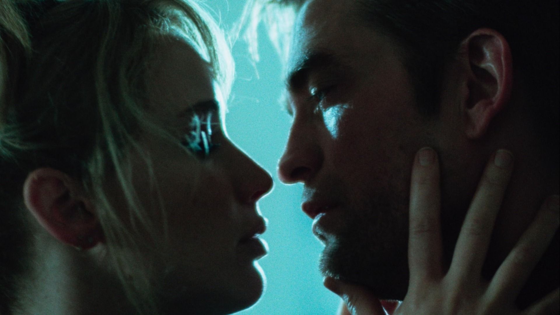 Gli attori Jennifer Lawrence e Robert Pattinson si guardano negli occhi su sfondo blu