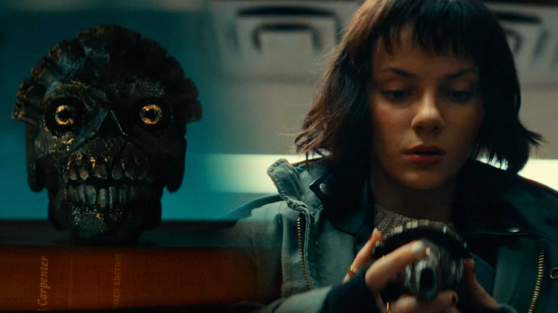 Teschio di metallo, a destra l'attrice Dafne Keen in giacca verde tiene questo teschio tra le mani