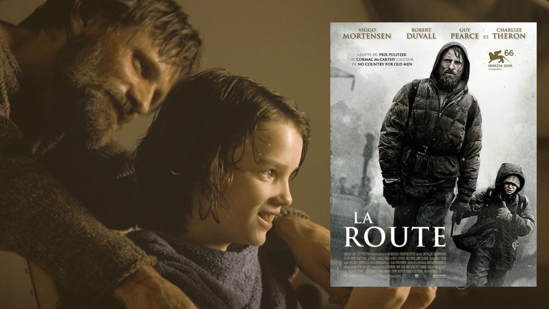 L'attore Viggo Mortensen in maglione grigio seduto accanto a un bambino, nelle vicinanze c'è un poster del film che mostra l'attore camminare per strada con un bambino