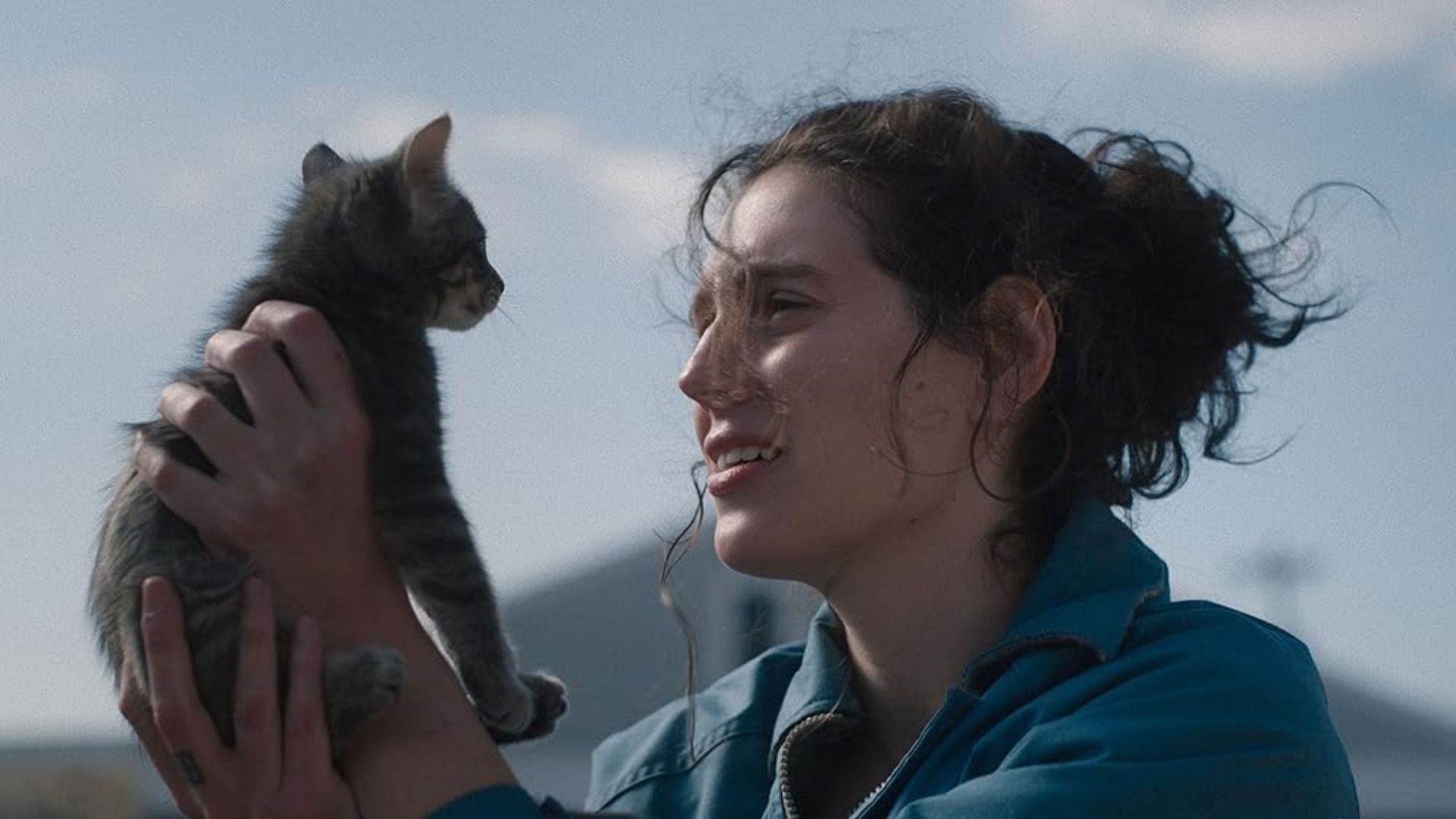 Una ragazza in giacca blu tiene un gattino e lo guarda