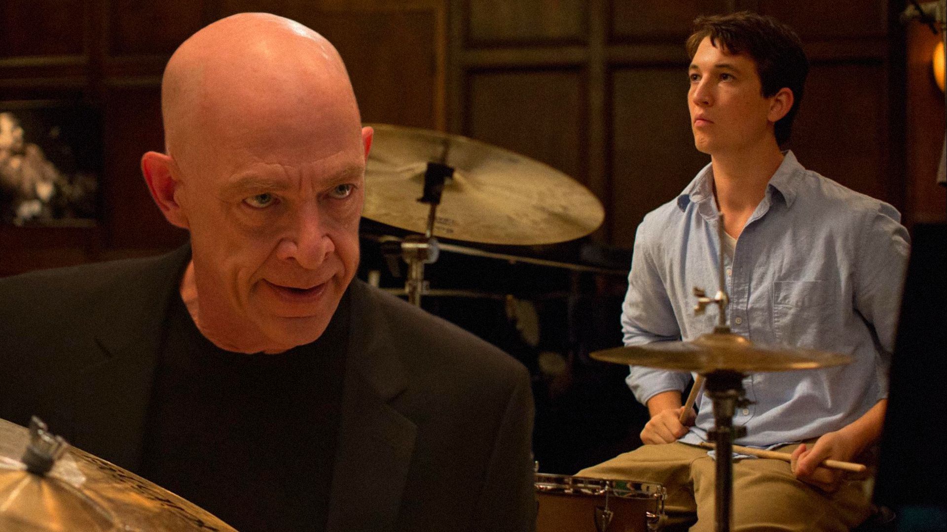 L'attore Miles Teller suona dietro una batteria mentre l'attore J.K. Simmons lo guarda minacciosamente dall'alto