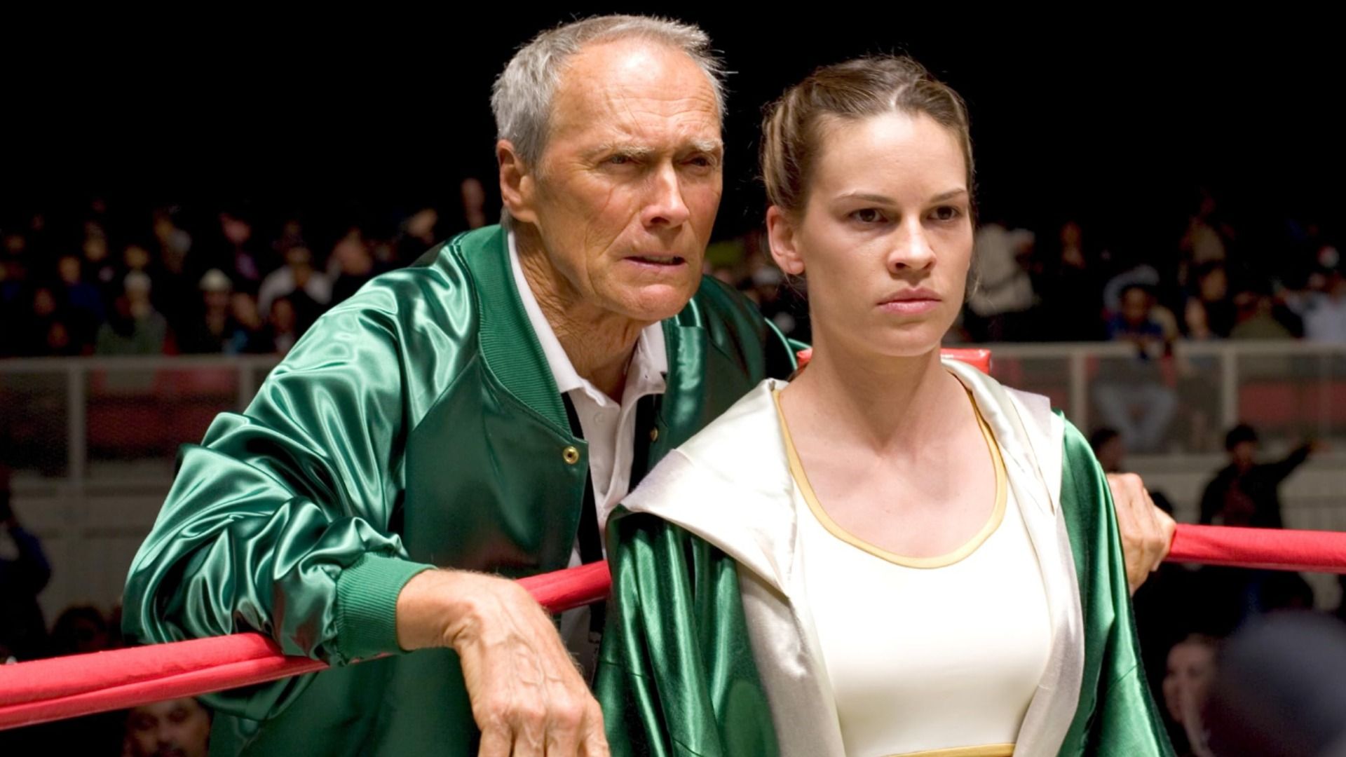 Gli attori Clint Eastwood e Hilary Swank in piedi con abiti verdi su un ring da boxe