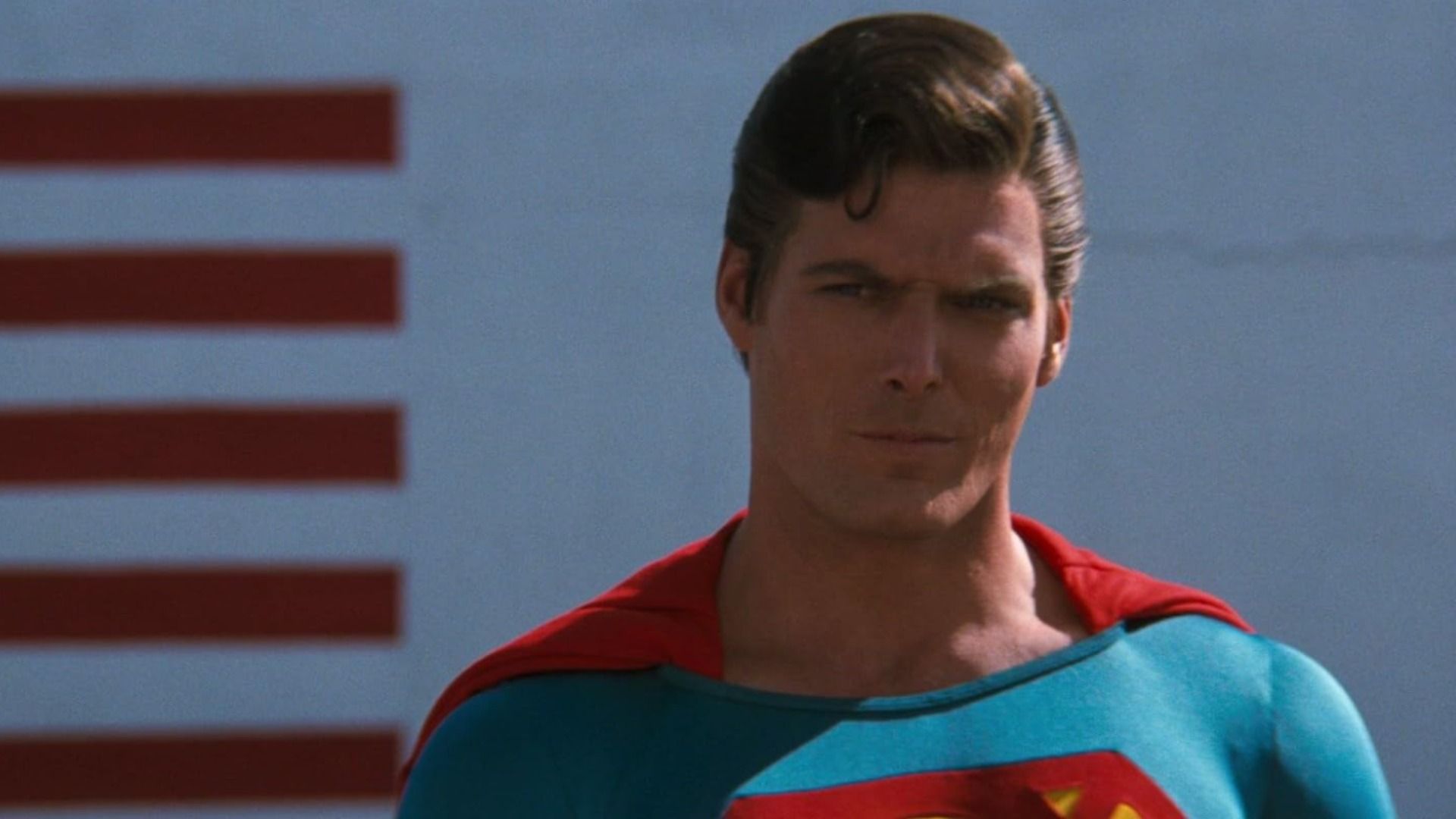 L'attore Christopher Reeve nel costume blu e rosso di Superman guarda minacciosamente di lato
