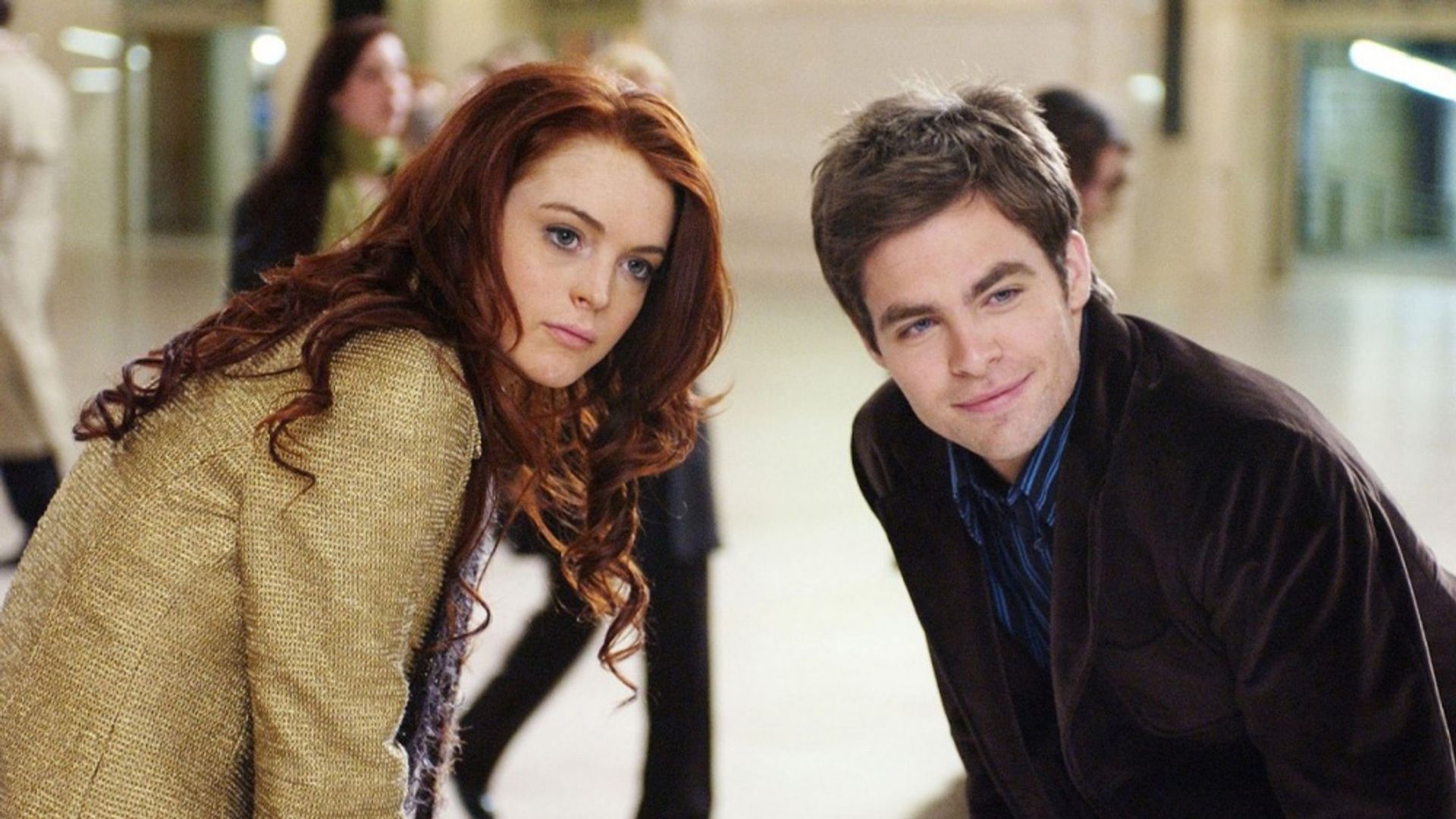 Lindsay Lohan e Chris Pine stanno fianco a fianco, piegati in avanti in una stanza affollata