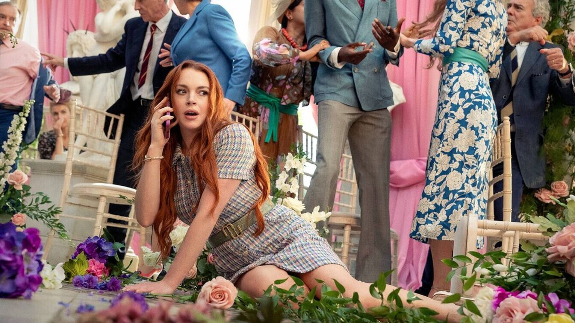Lindsay Lohan è caduta a terra tra i fiori mentre parla al telefono con il caos della cerimonia nuziale sullo sfondo