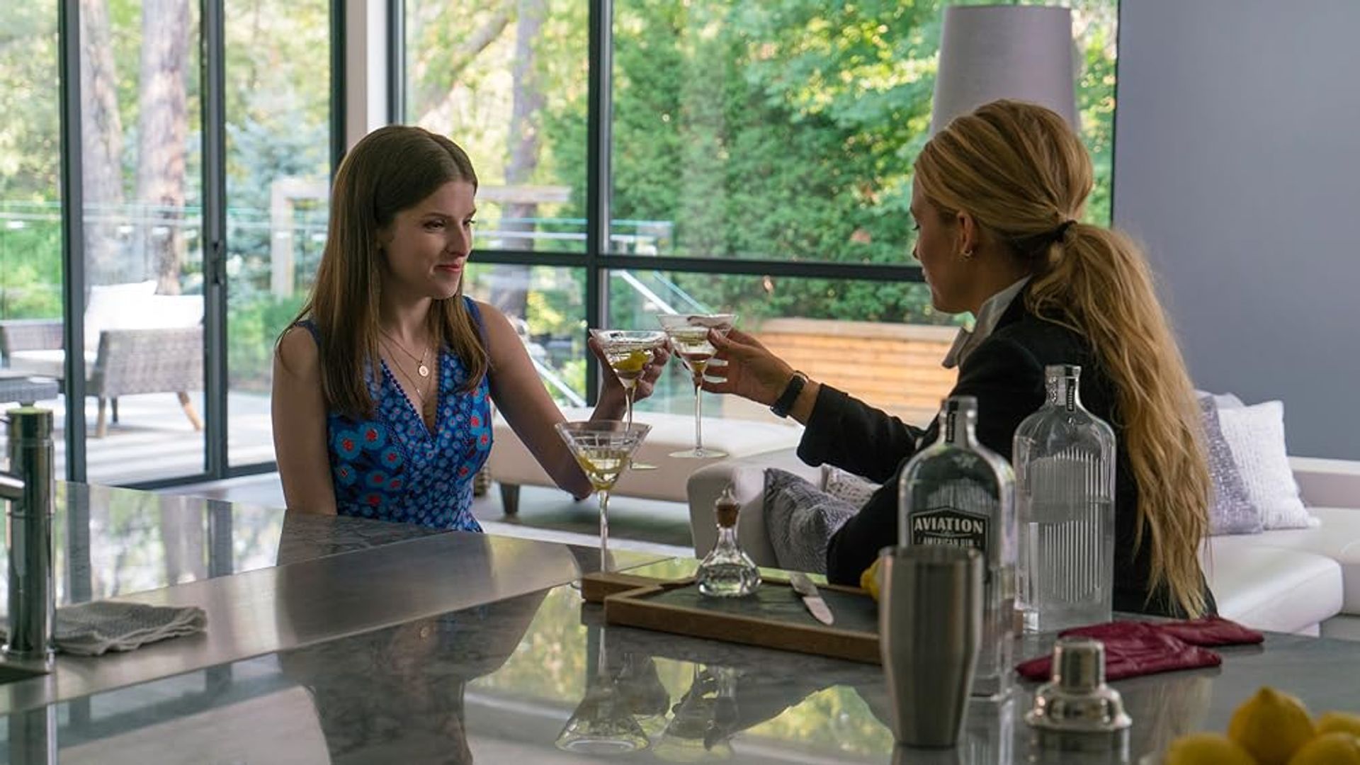 Anna Kendrick e Blake Lively che brindano con bicchieri di vino sedute in cucina