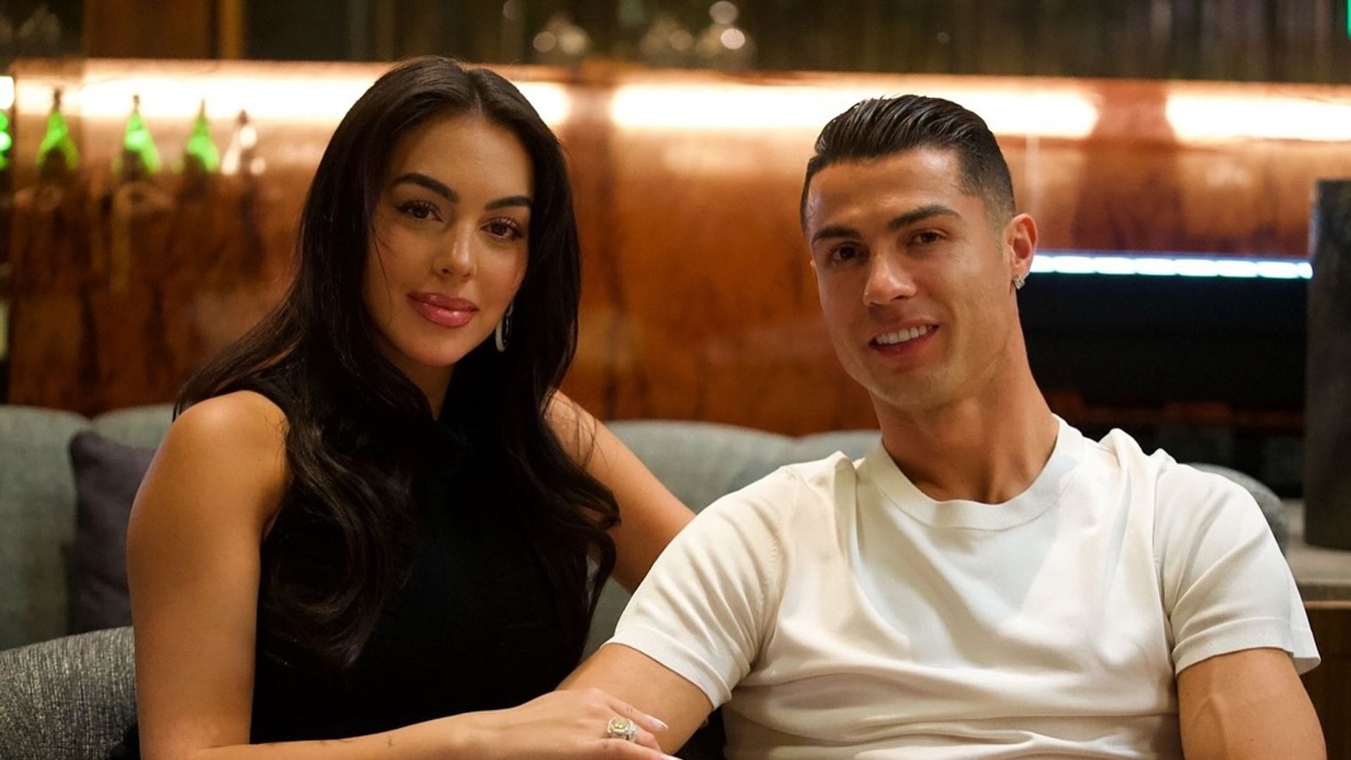 Georgina Rodriguez e Cristiano Ronaldo seduti insieme e sorridenti davanti alla fotocamera