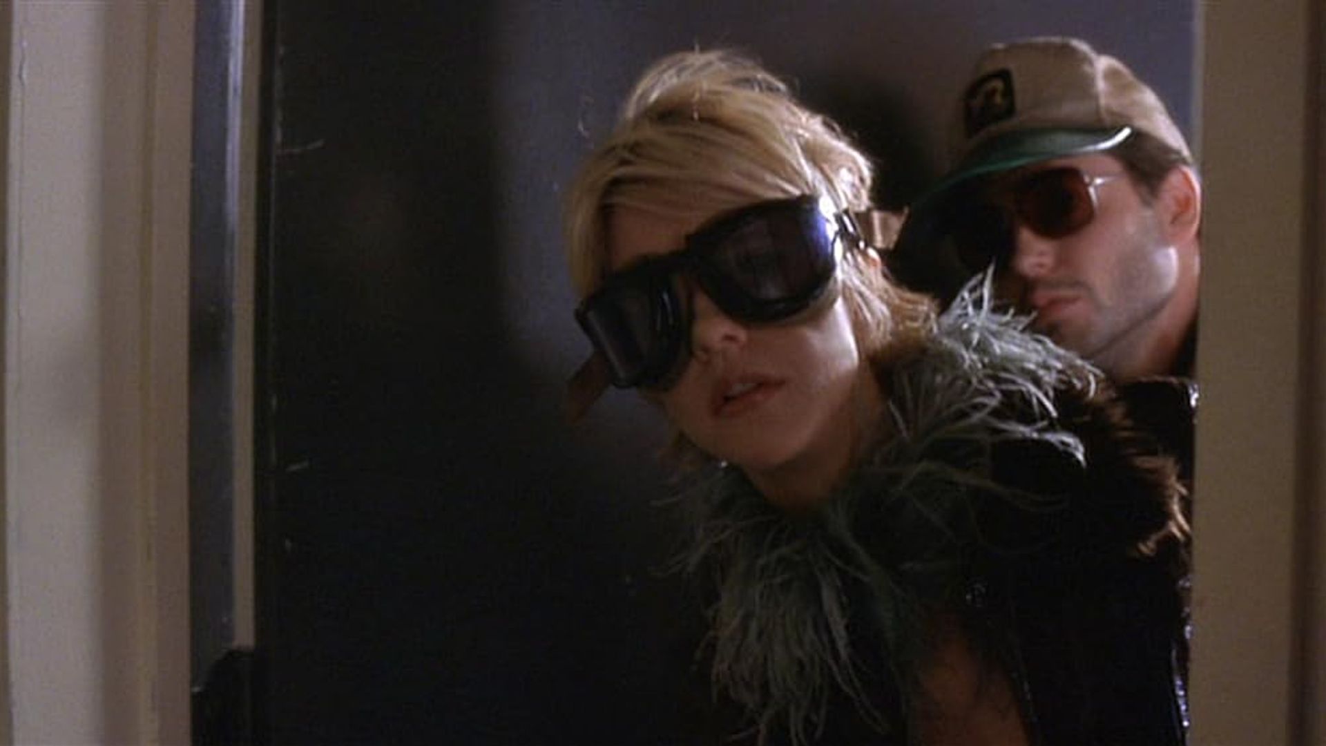 Meg Ryan e Matthew Broderick con occhiali da sole scuri che spuntano da dietro una porta