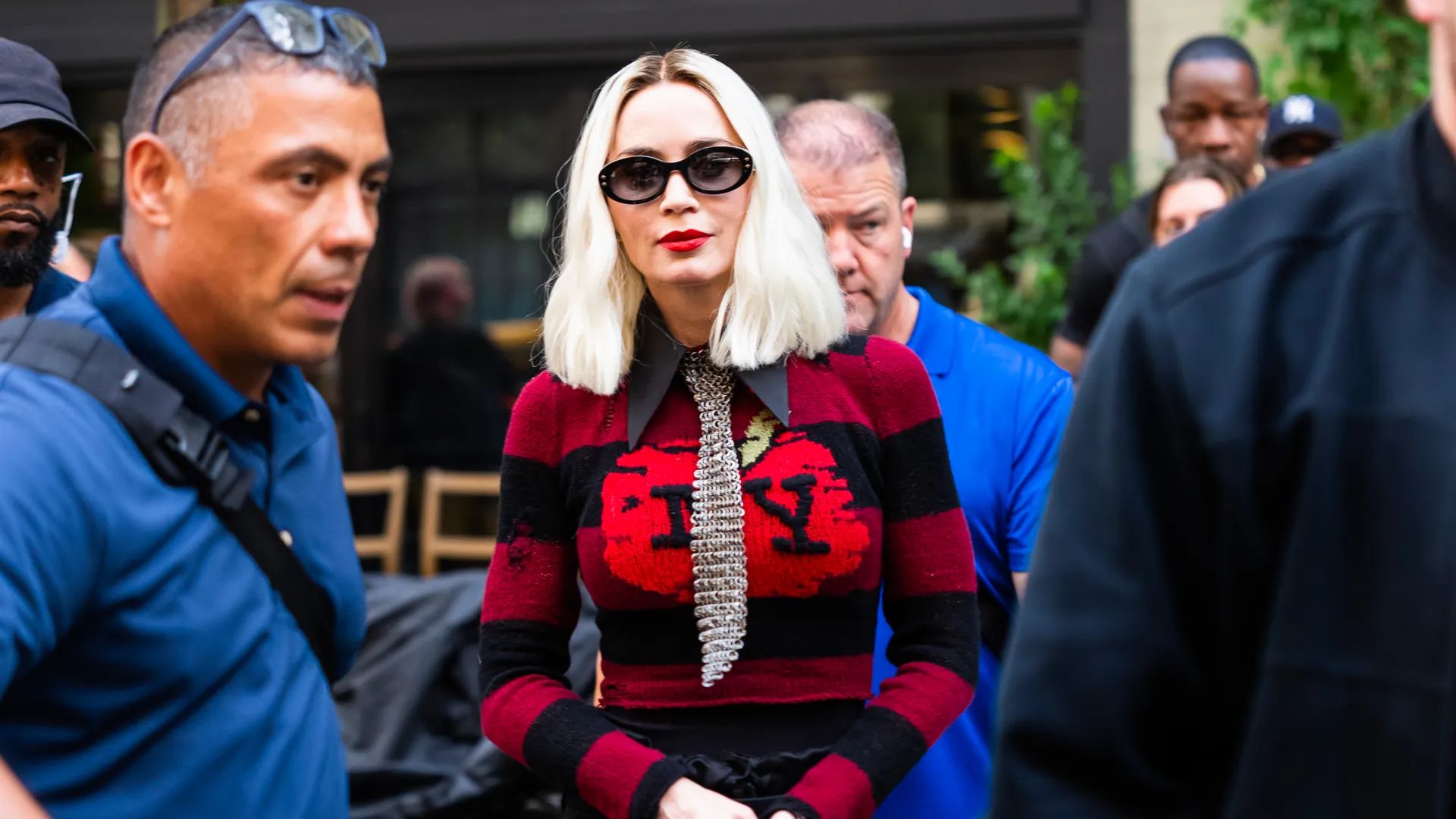 Emily Blunt con caschetto platino in maglione rosso con scritta NY