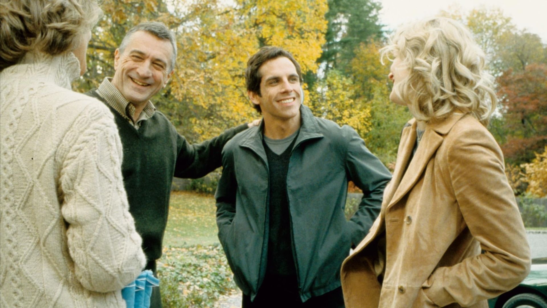 Gli attori Robert De Niro in maglione verde e Ben Stiller in giacca verde in piedi accanto ad alberi con foglie gialle