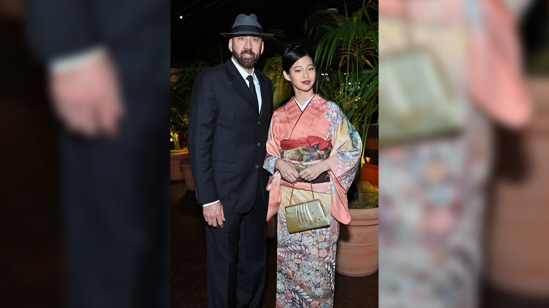 Nicolas Cage in abito nero e cappello e Riko Shibata in kimono rosa fantasia