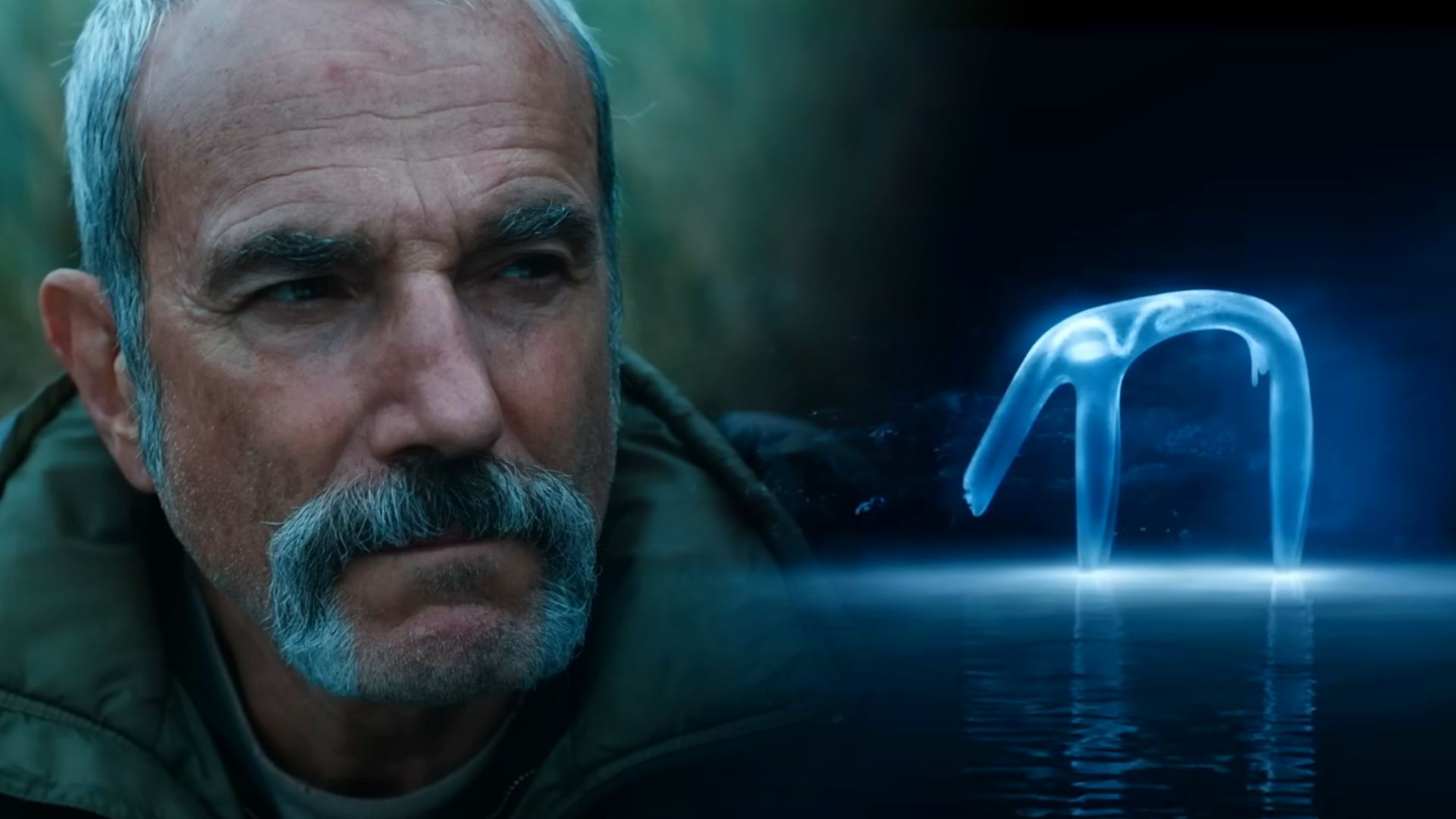 L'attore Daniel Day-Lewis in giacca verde e una creatura traslucida bluastra in piedi sull'acqua