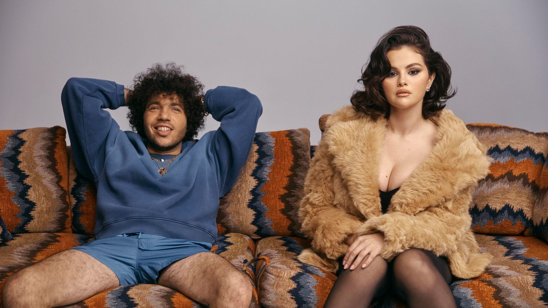 Selena Gomez in pelliccia e Benny Blanco in felpa blu e pantaloncini seduti rilassati