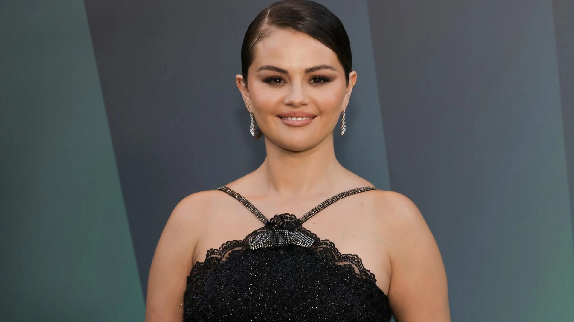 Selena Gomez in abito nero posa per le telecamere con un sorriso dolce