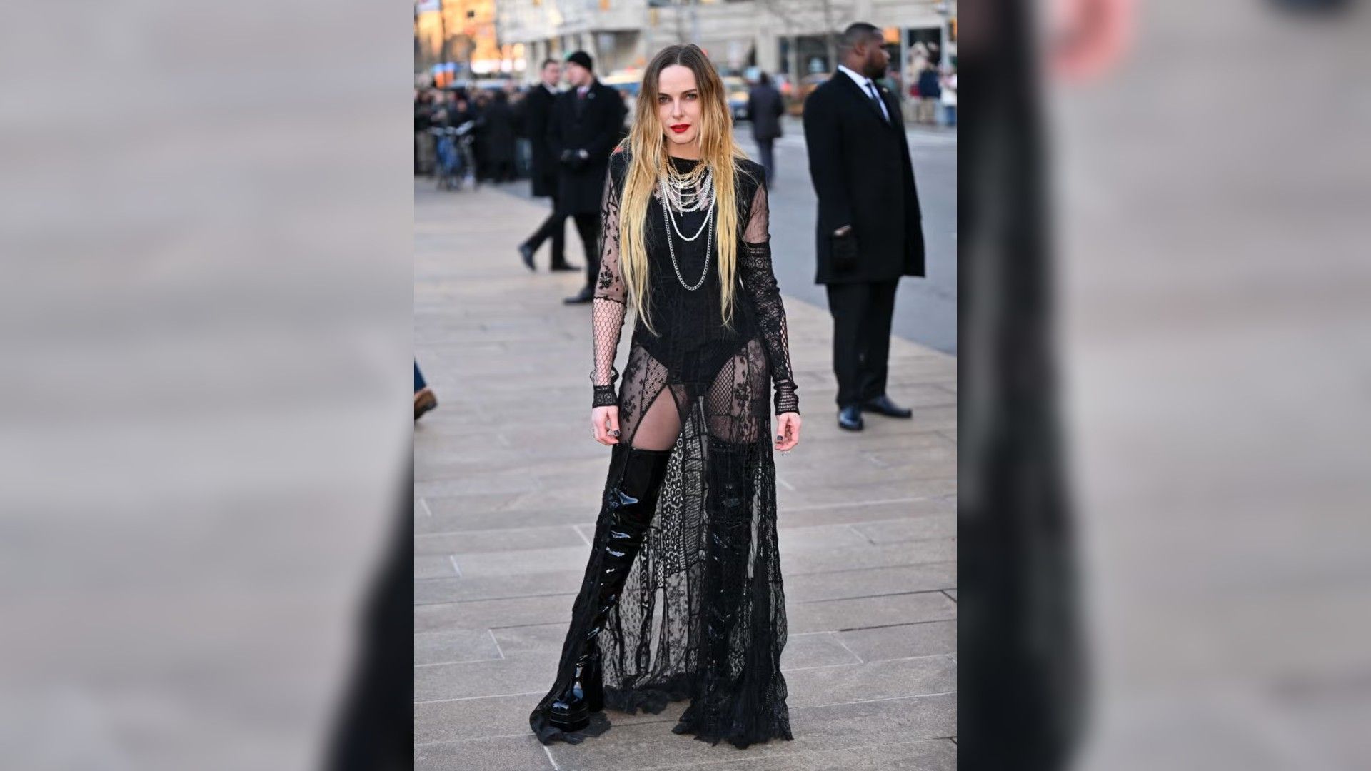 Rebecca Ferguson posa all'aperto in un lungo abito nero trasparente con pizzo e stivali alti di vernice.