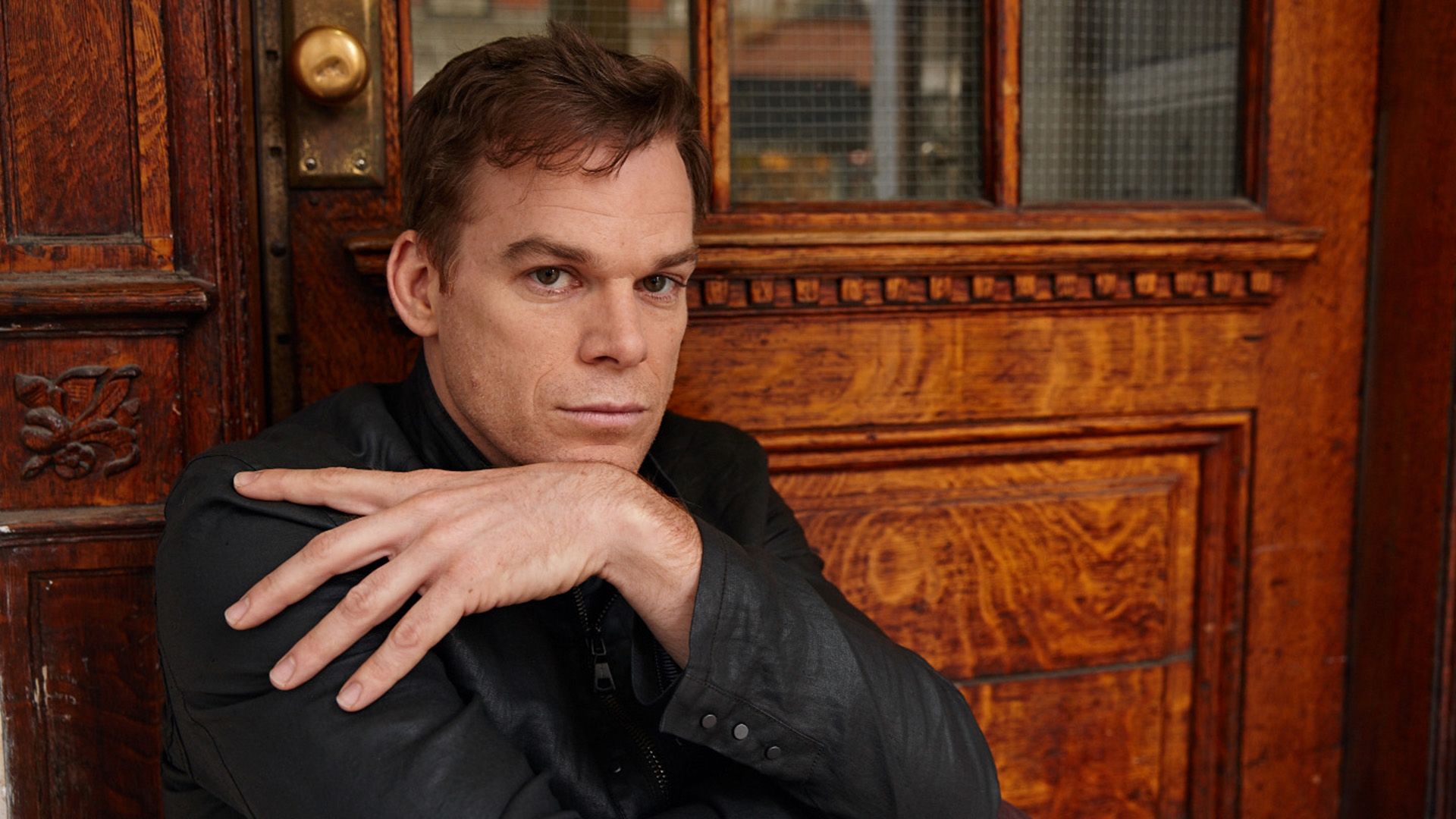 L'attore Michael C. Hall posa contro una porta di legno