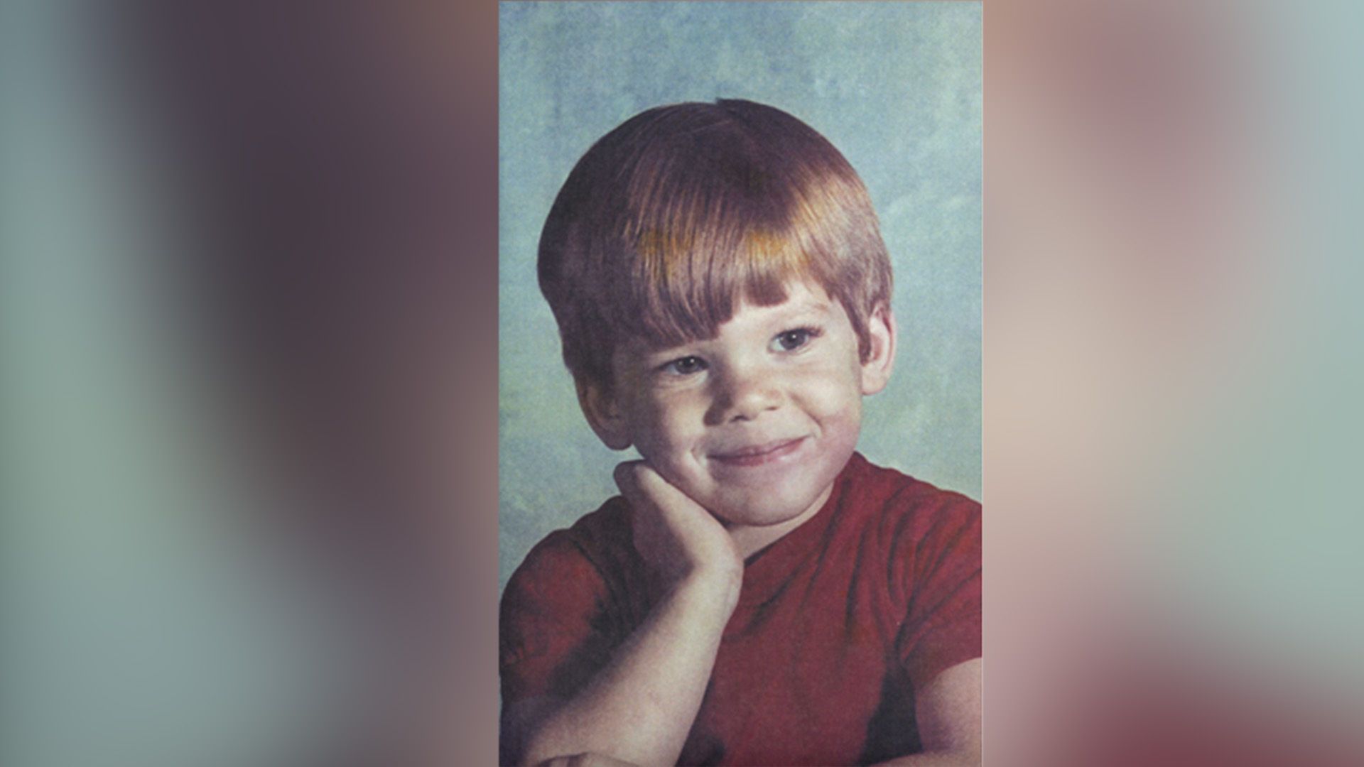 Michael C. Hall da bambino con una maglietta rossa che guarda di lato