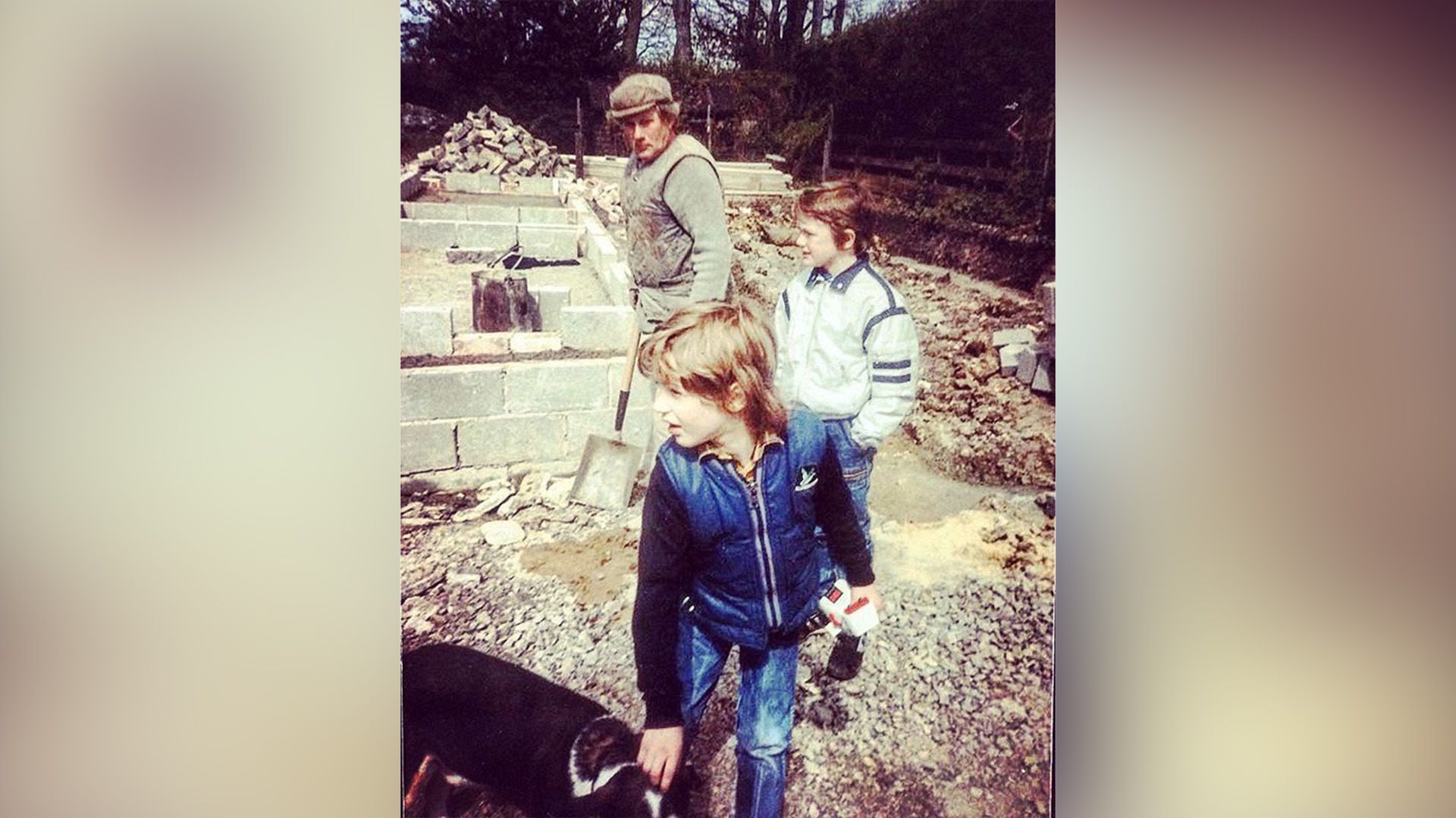 Il piccolo Tom Hardy accarezza un cane in giardino con il cugino e il nonno accanto