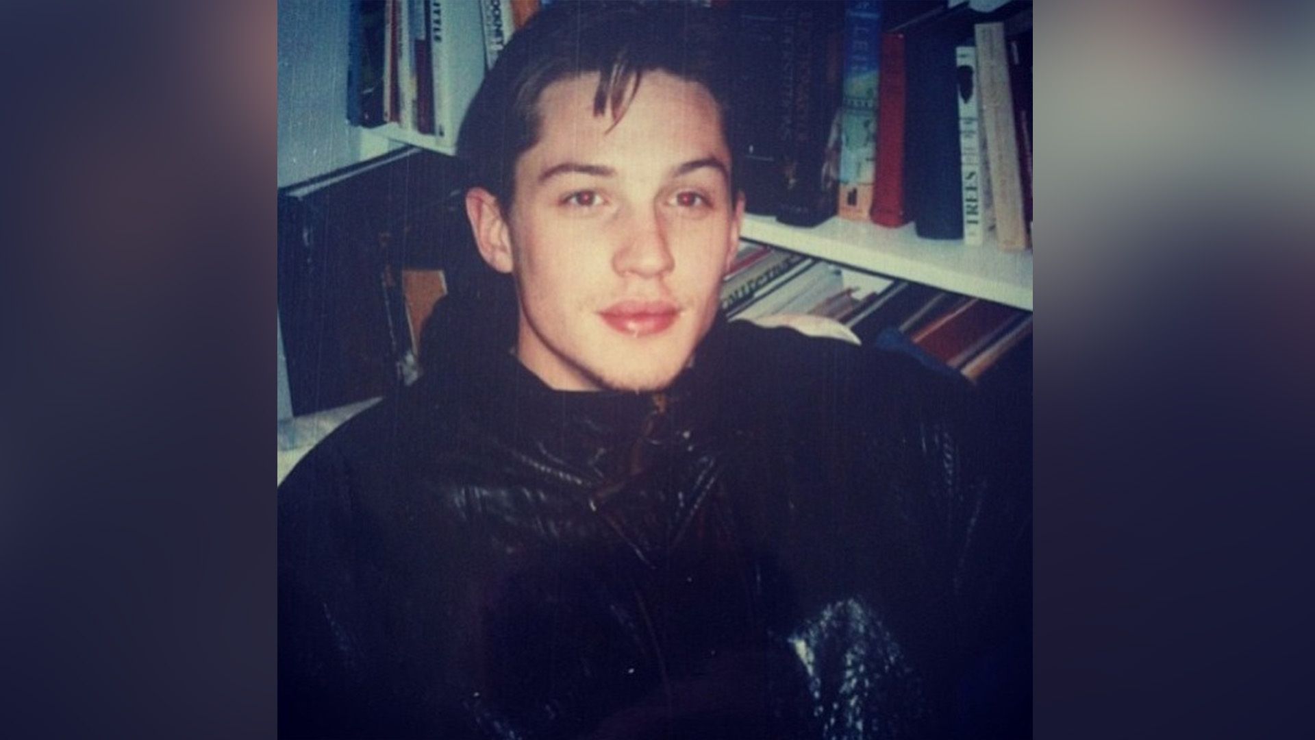 Il giovane Tom Hardy accanto a una libreria