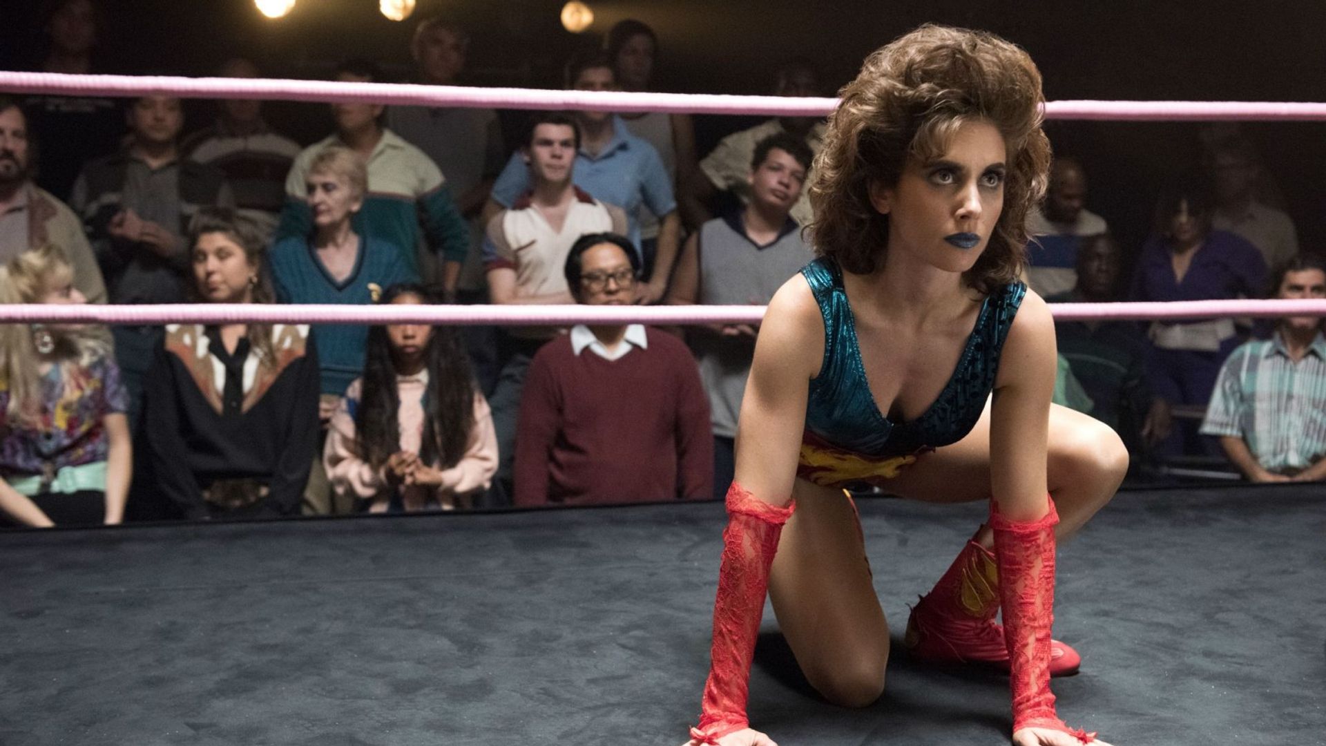 Alison Brie in costume da wrestler seduta in posizione sul ring