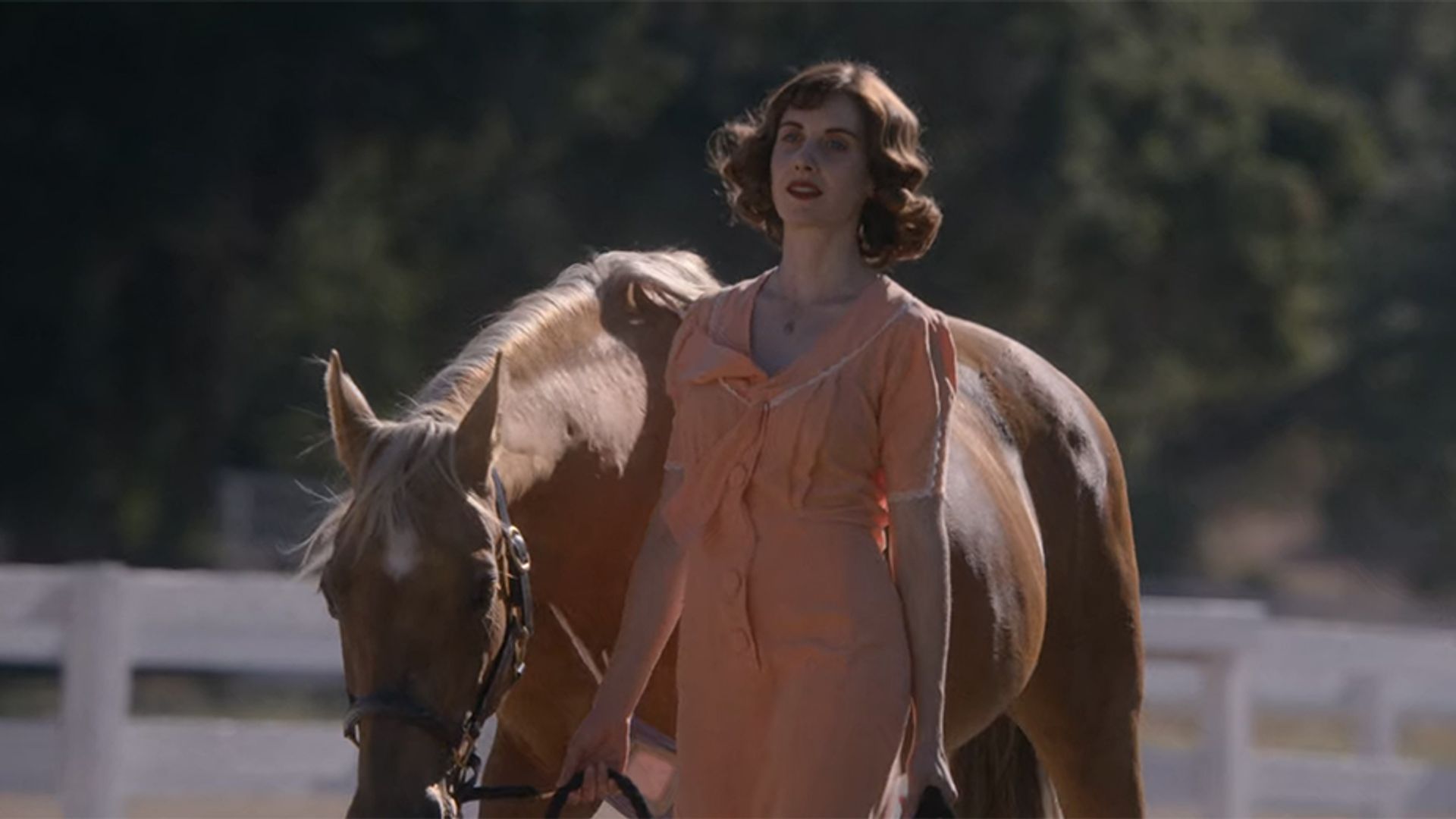 Alison Brie che conduce un cavallo per le redini, fotogramma dal film "Horse Girl"