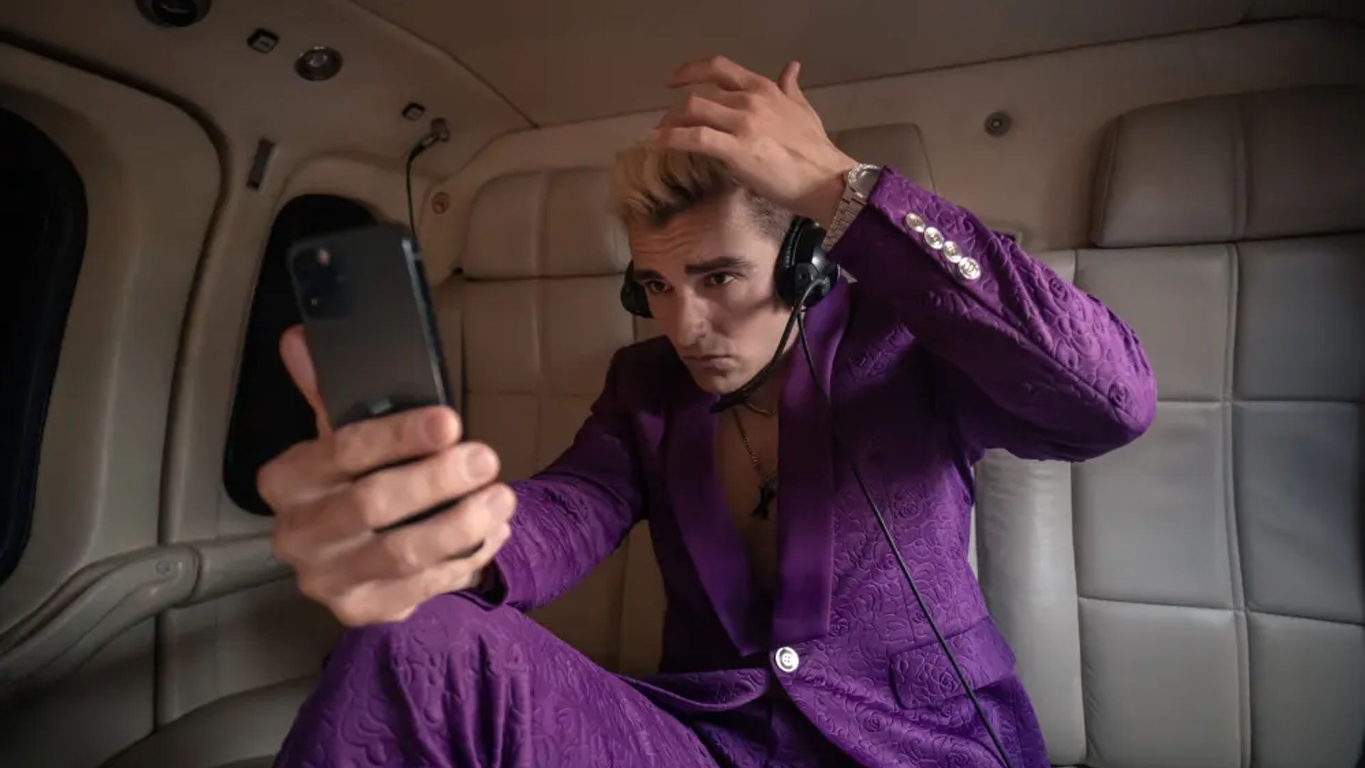 Dave Franco in un completo viola che guarda il telefono, scena dalla serie The Afterparty