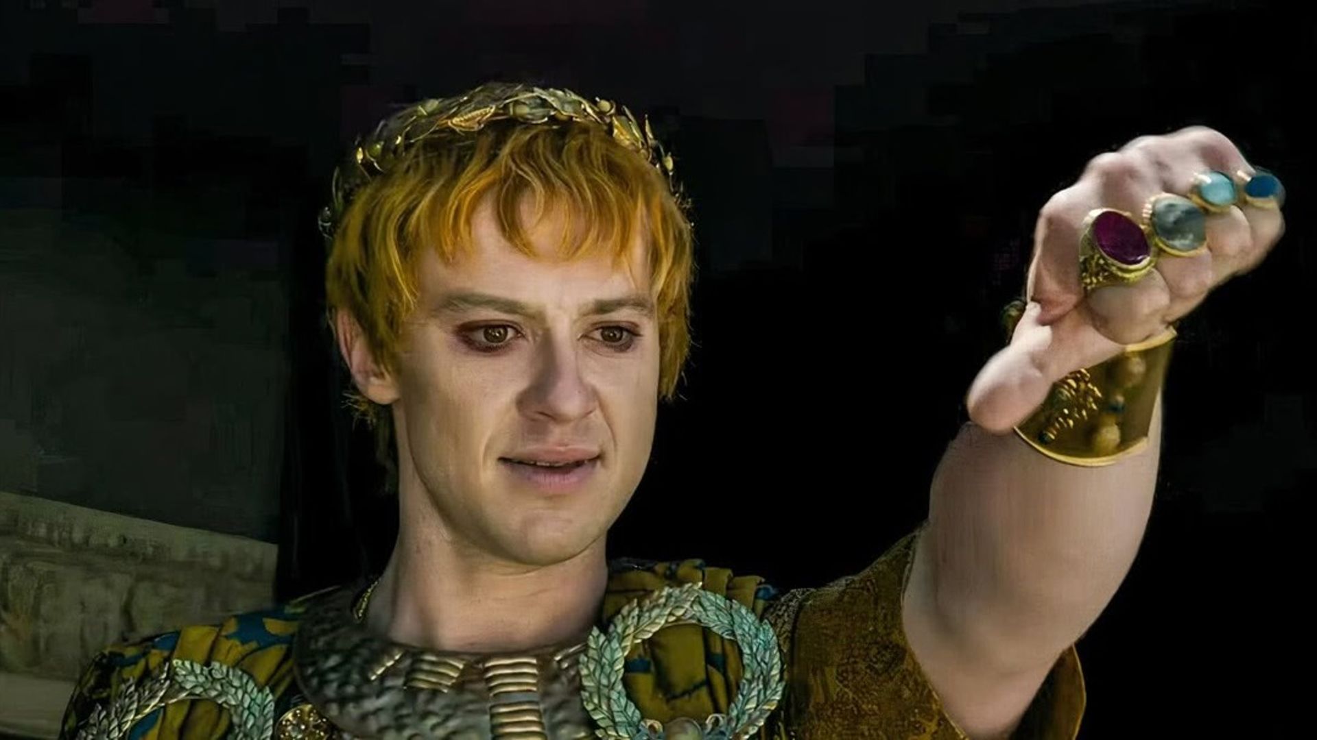 Joseph Quinn in trucco e costume da imperatore romano mostra il gesto del pollice verso il basso