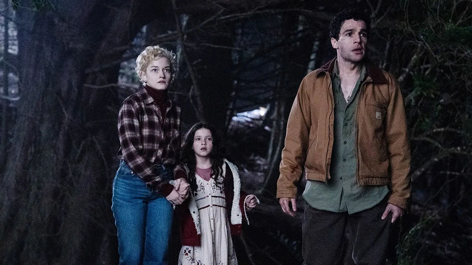 Julia Garner, Christopher Abbott e Matilda Firth in una foresta notturna, still dal film "Wolf Man"