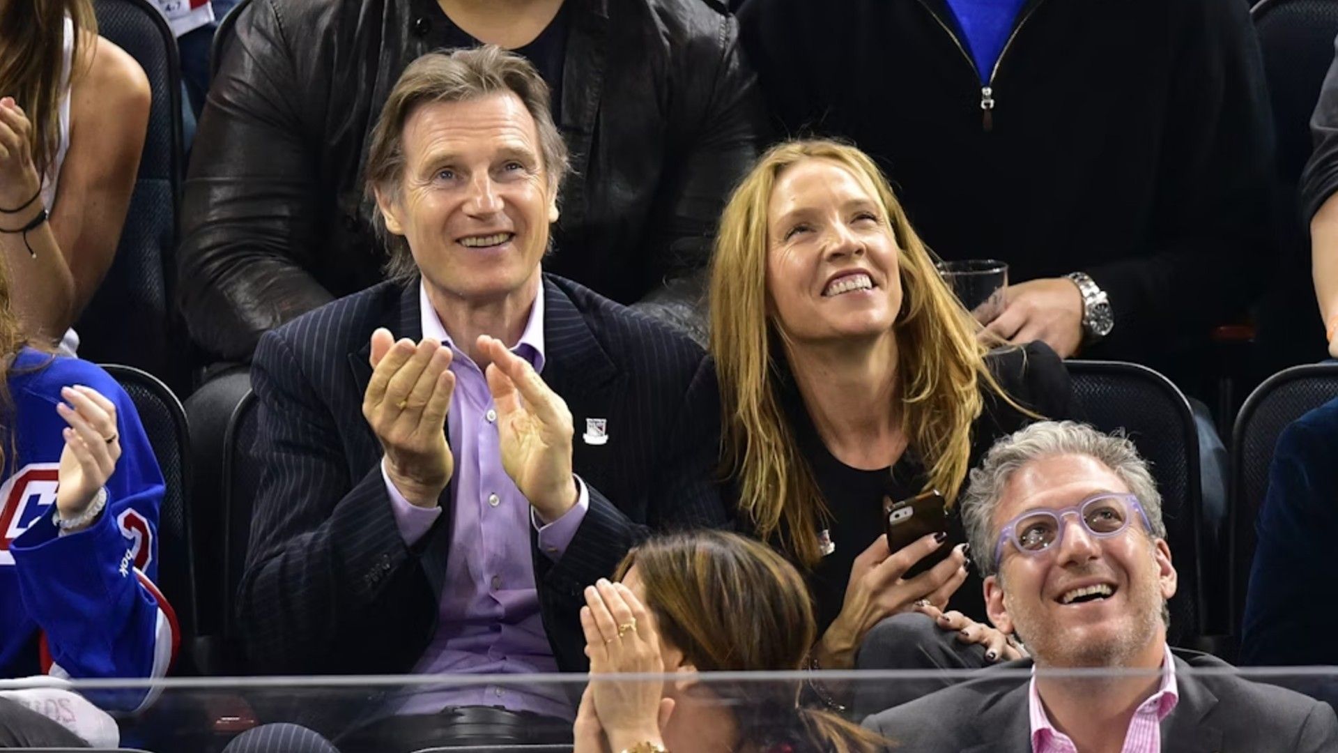 Liam Neeson e Freya St. Johnston seduti sugli spalti durante una partita sportiva mentre esultano con gioia