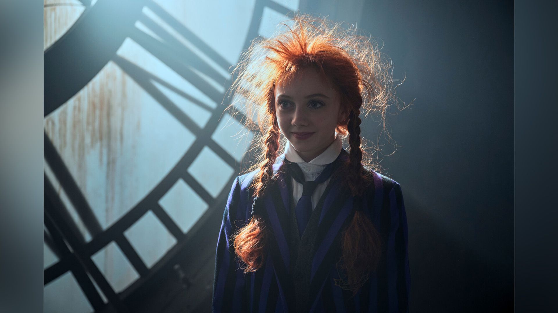 Evie Templeton con trecce rosse e capelli spettinati, indossando un blazer a righe nere e viola