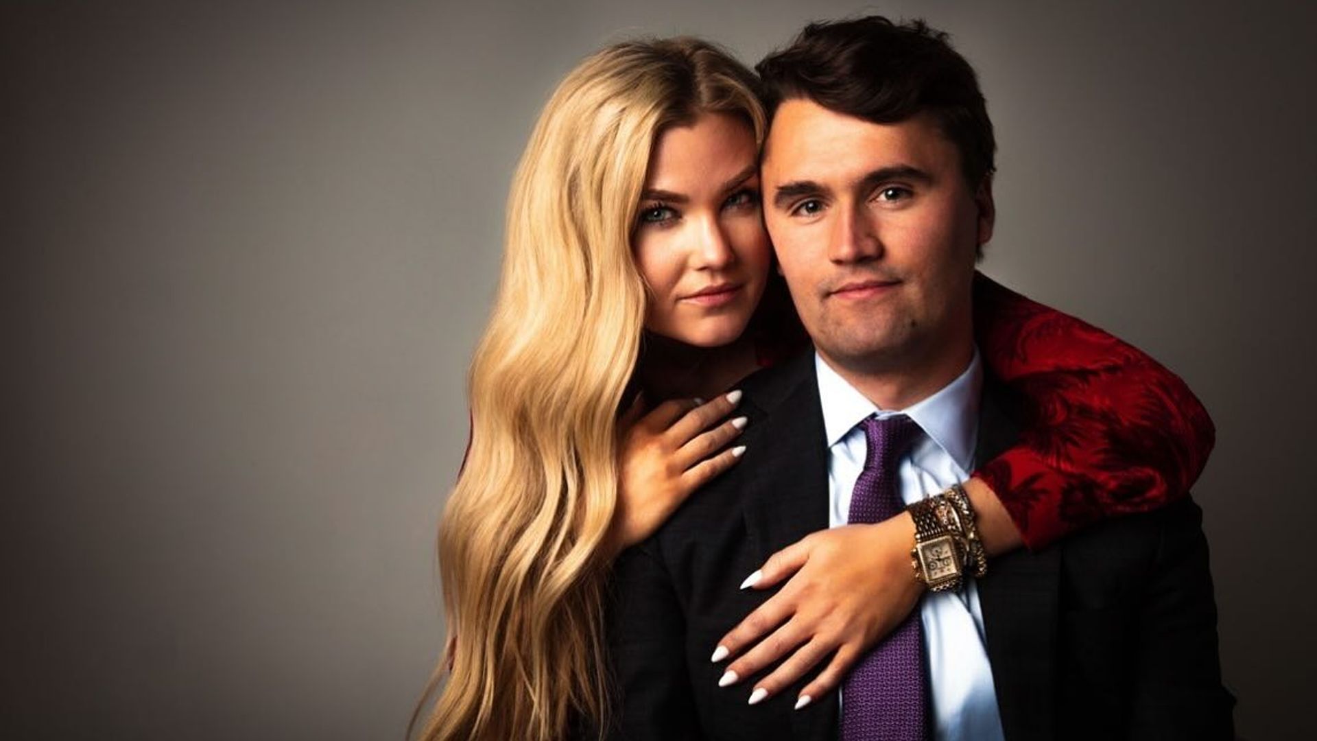 Charlie Kirk ed Erica Frantzve si abbracciano davanti alla telecamera su uno sfondo scuro