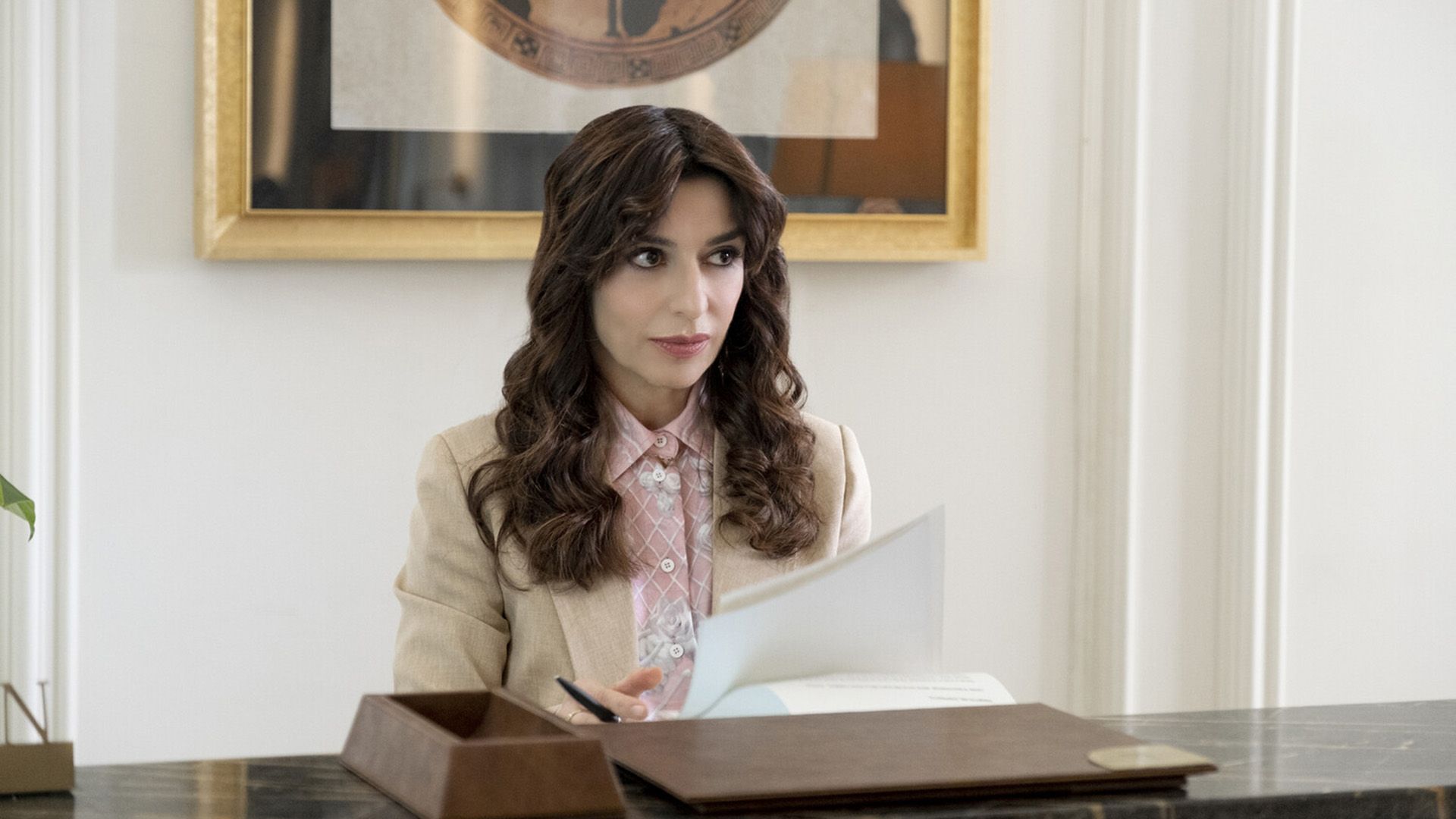 Sabrina Impacciatore con un blazer beige che tiene una penna e un foglio