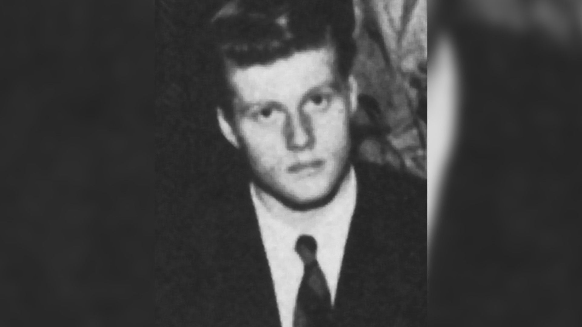 Un ritratto in bianco e nero del giovane Robert Redford in giacca e cravatta, che guarda direttamente verso la macchina fotografica.