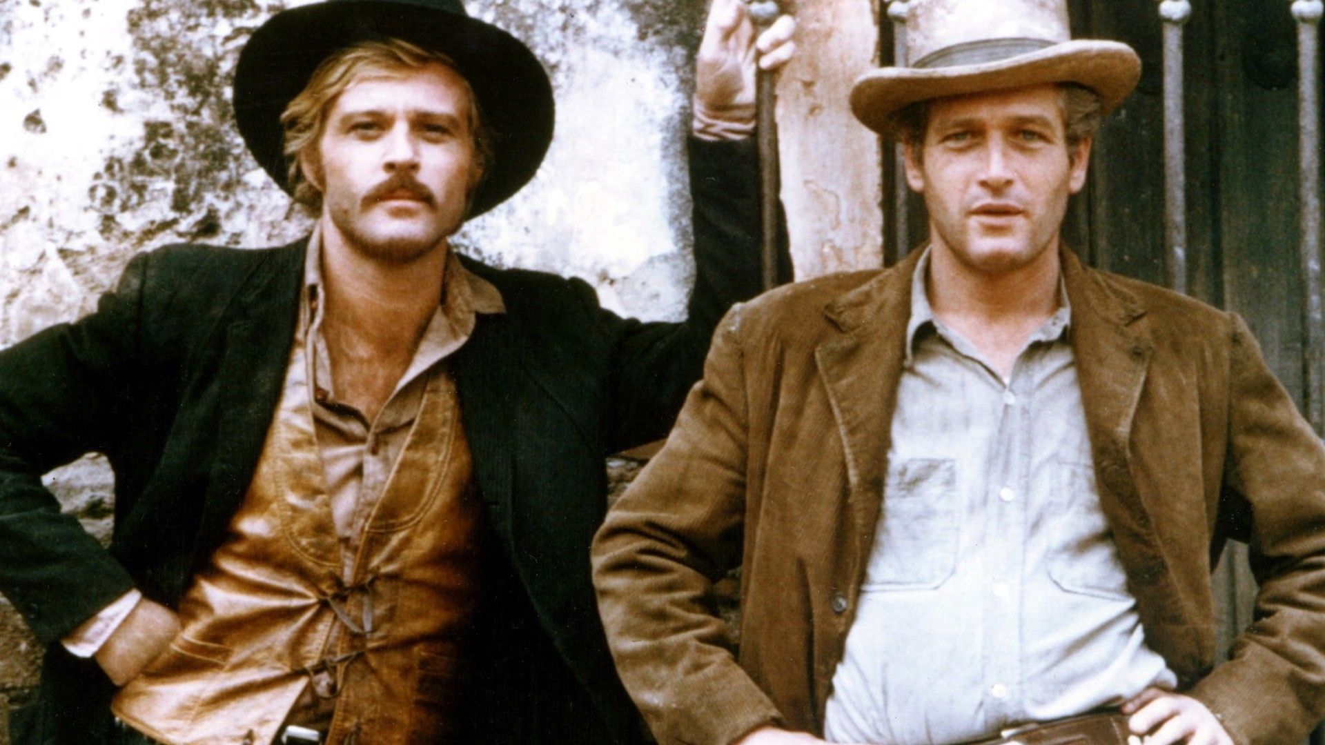 Robert Redford e Paul Newman con cappelli da cowboy e giacche in piedi uno accanto all'altro contro un muro, in posa per una foto