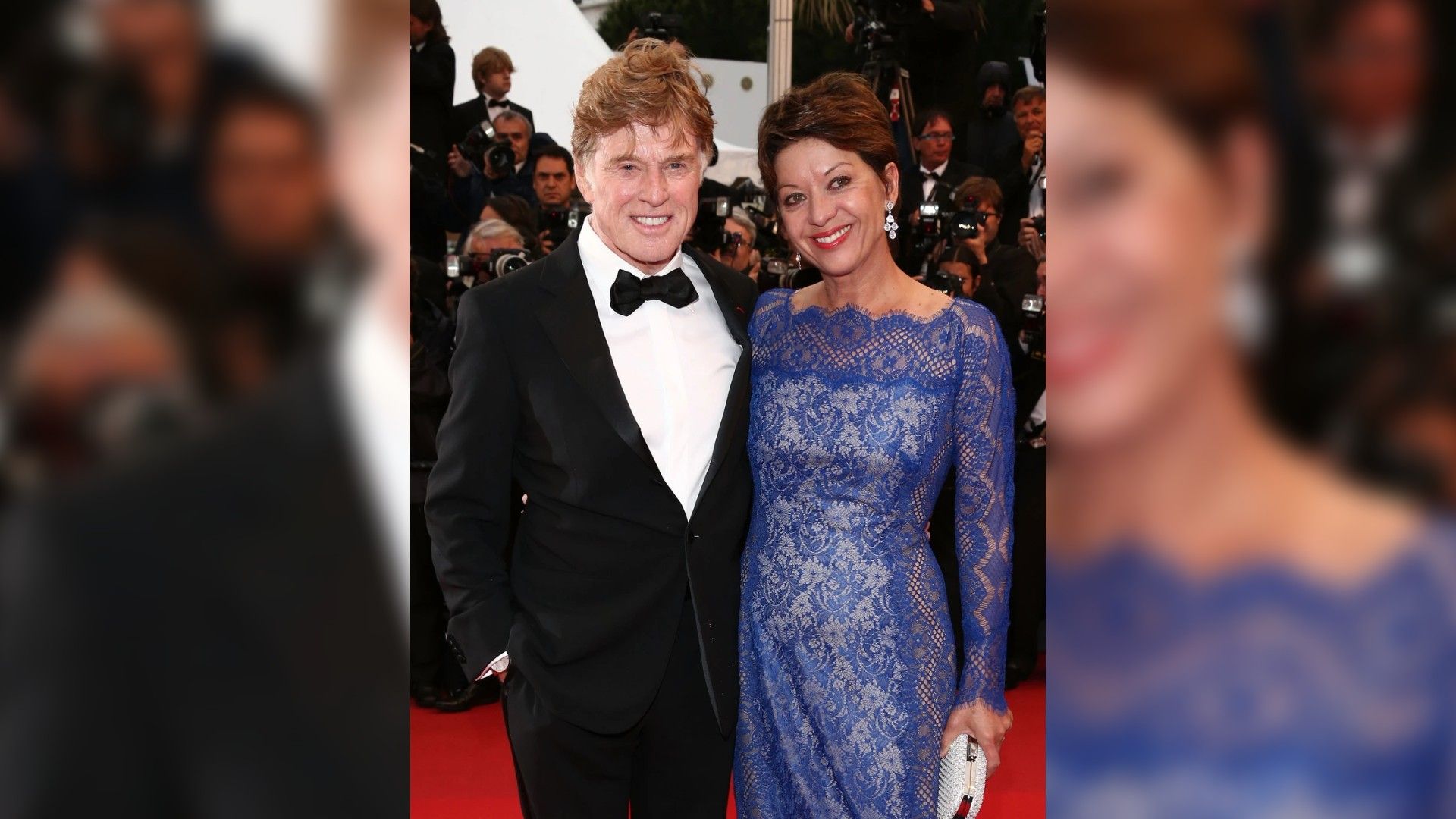 Robert Redford in smoking e Sibylle Szaggars in un abito di pizzo blu posano sul red carpet circondati dai fotografi