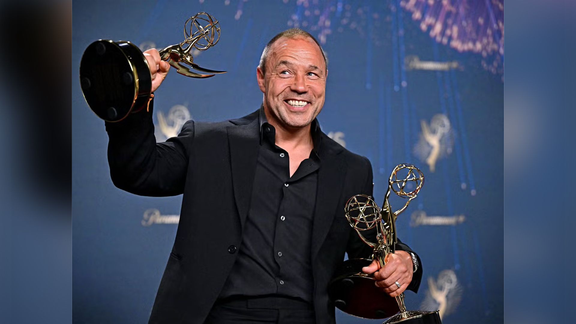 Stephen Graham in smoking nero tiene in mano tre statuette dorate degli Emmy, sorridendo ampiamente