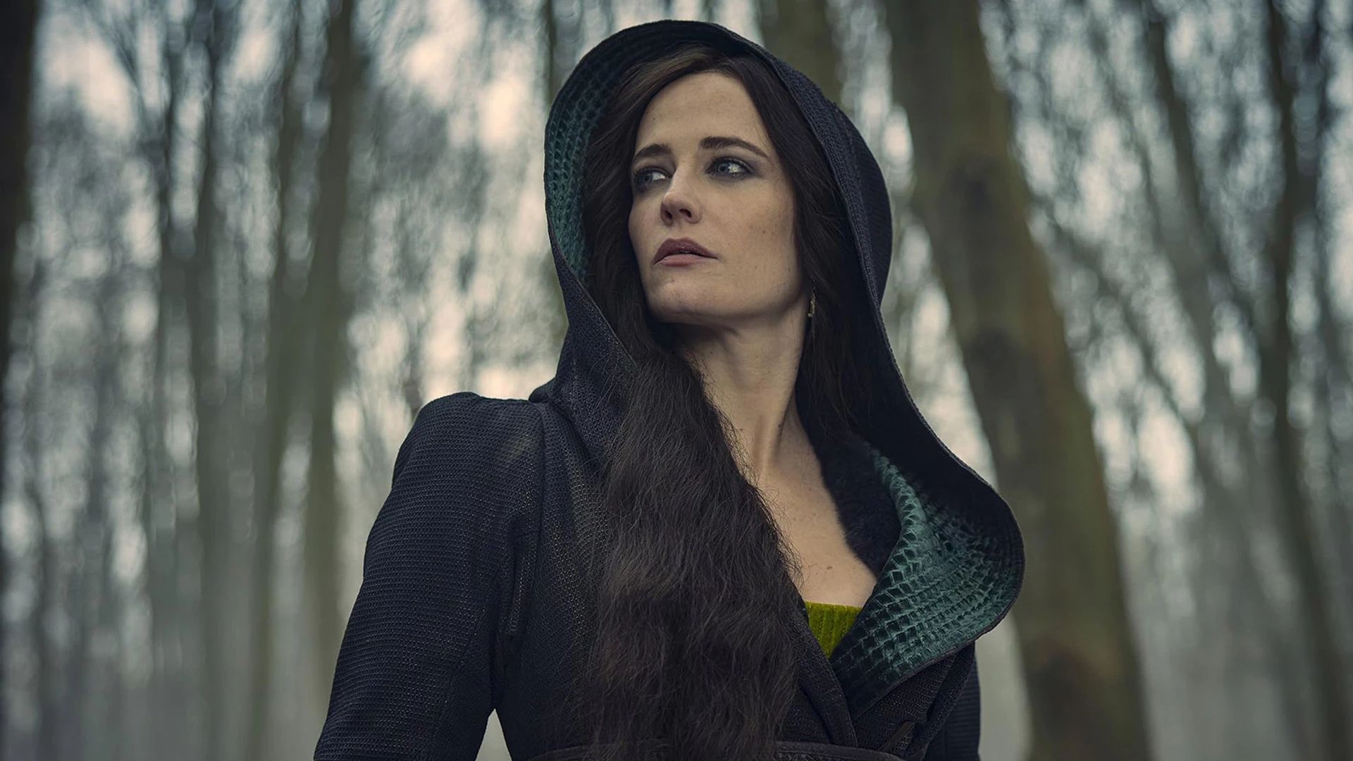 Eva Green in un abito nero con cappuccio su uno sfondo di foresta invernale
