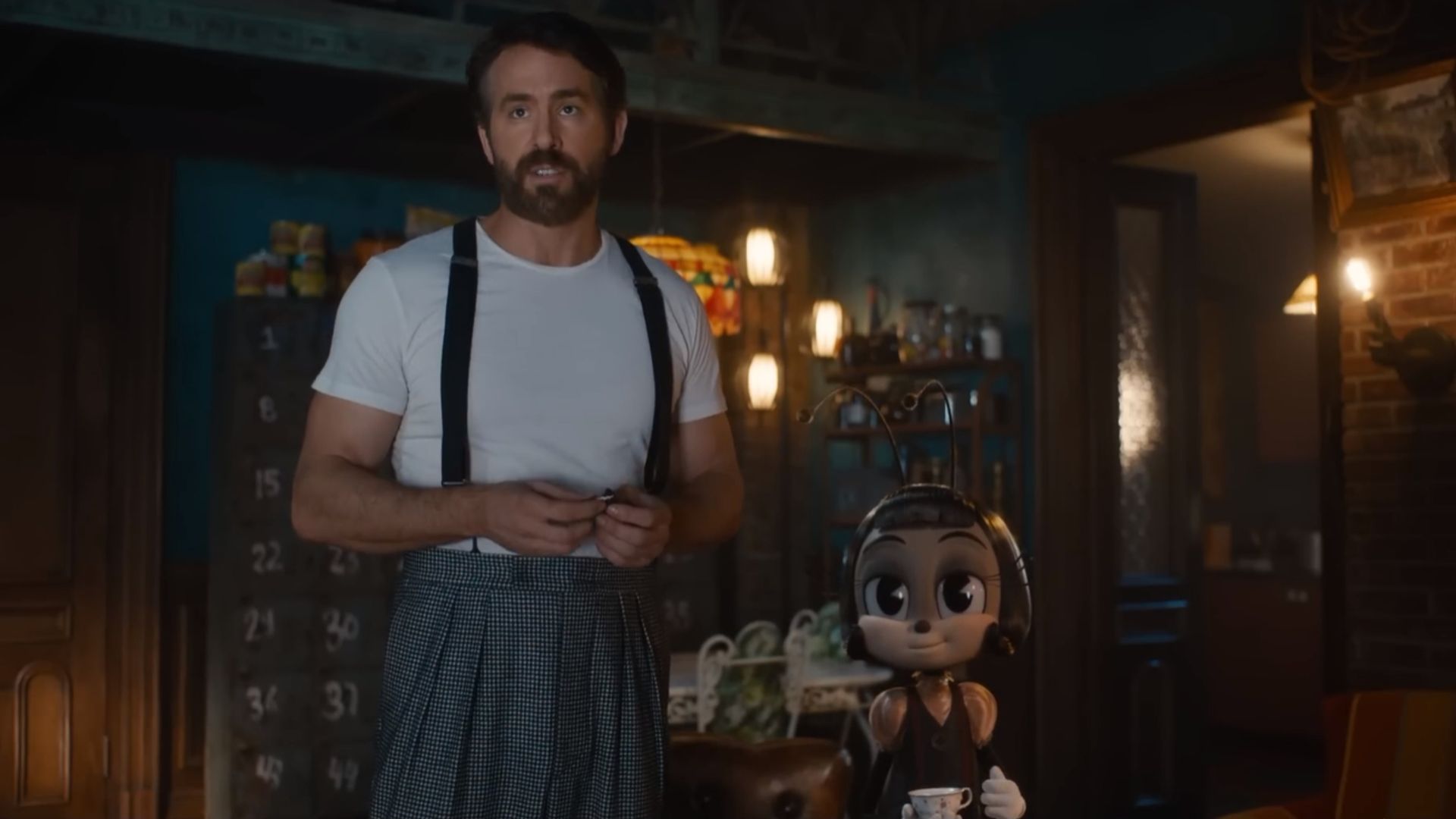 Ryan Reynolds in maglietta bianca con bretelle accanto a un personaggio cartoon di formica che tiene una tazza di tè