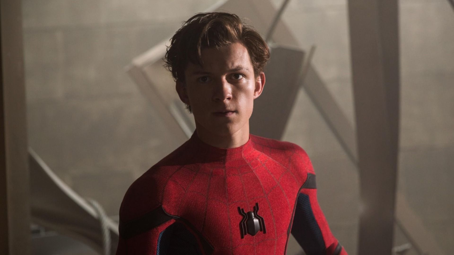 L'attore Tom Holland in costume da supereroe rosso con emblema del ragno sul petto