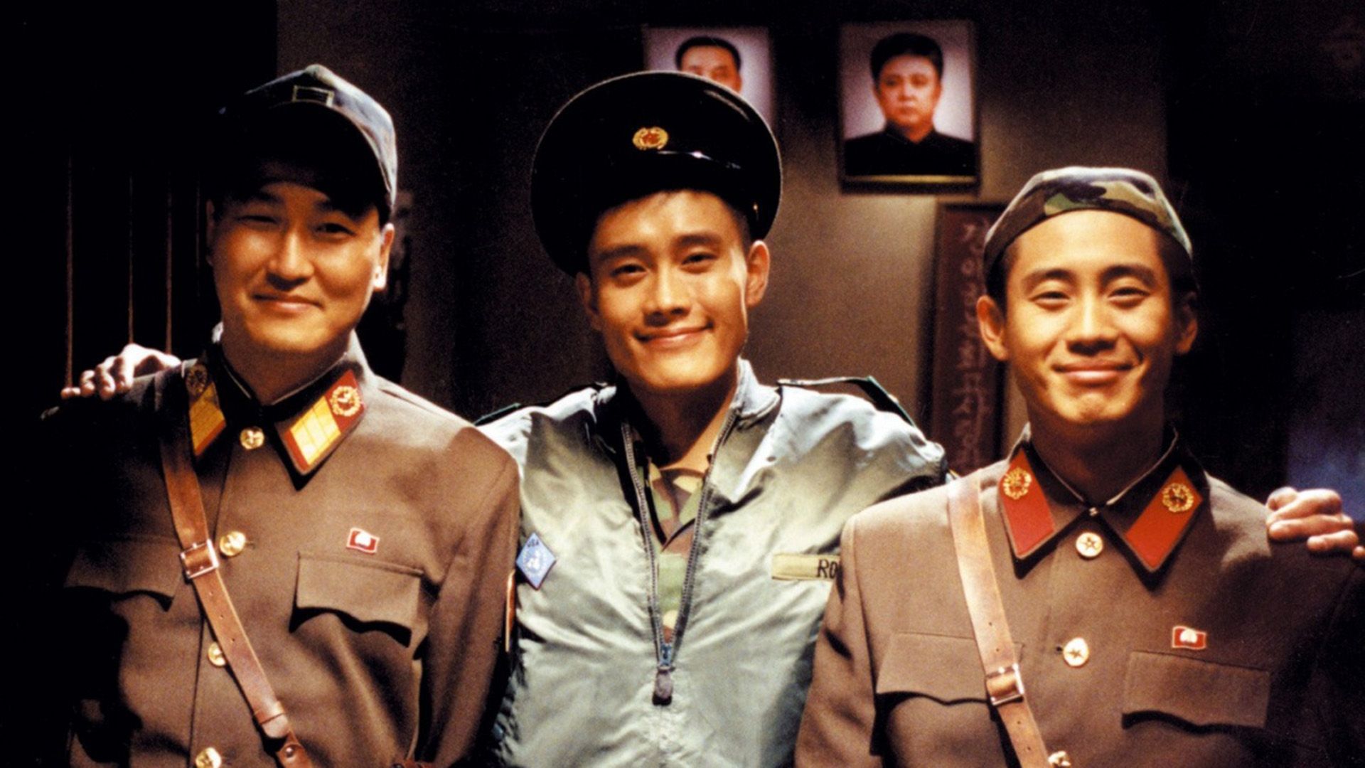 Lee Byung-hun abbraccia due uomini in uniforme militare, tutti e tre sorridono