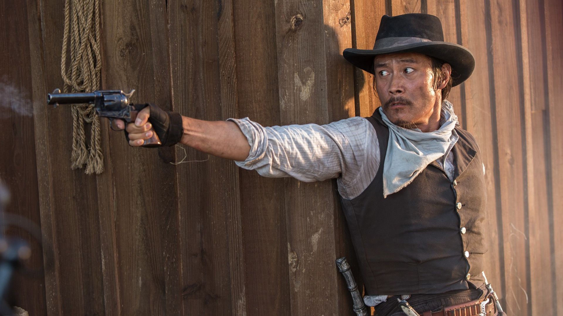 Lee Byung-hun in costume da cowboy e cappello spara con una pistola