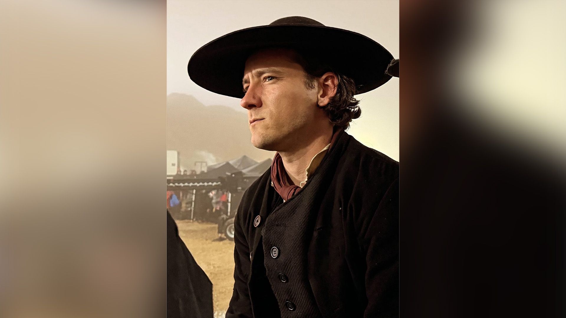 Lewis Pullman con giacca di lana nera e cappello nero a tesa larga