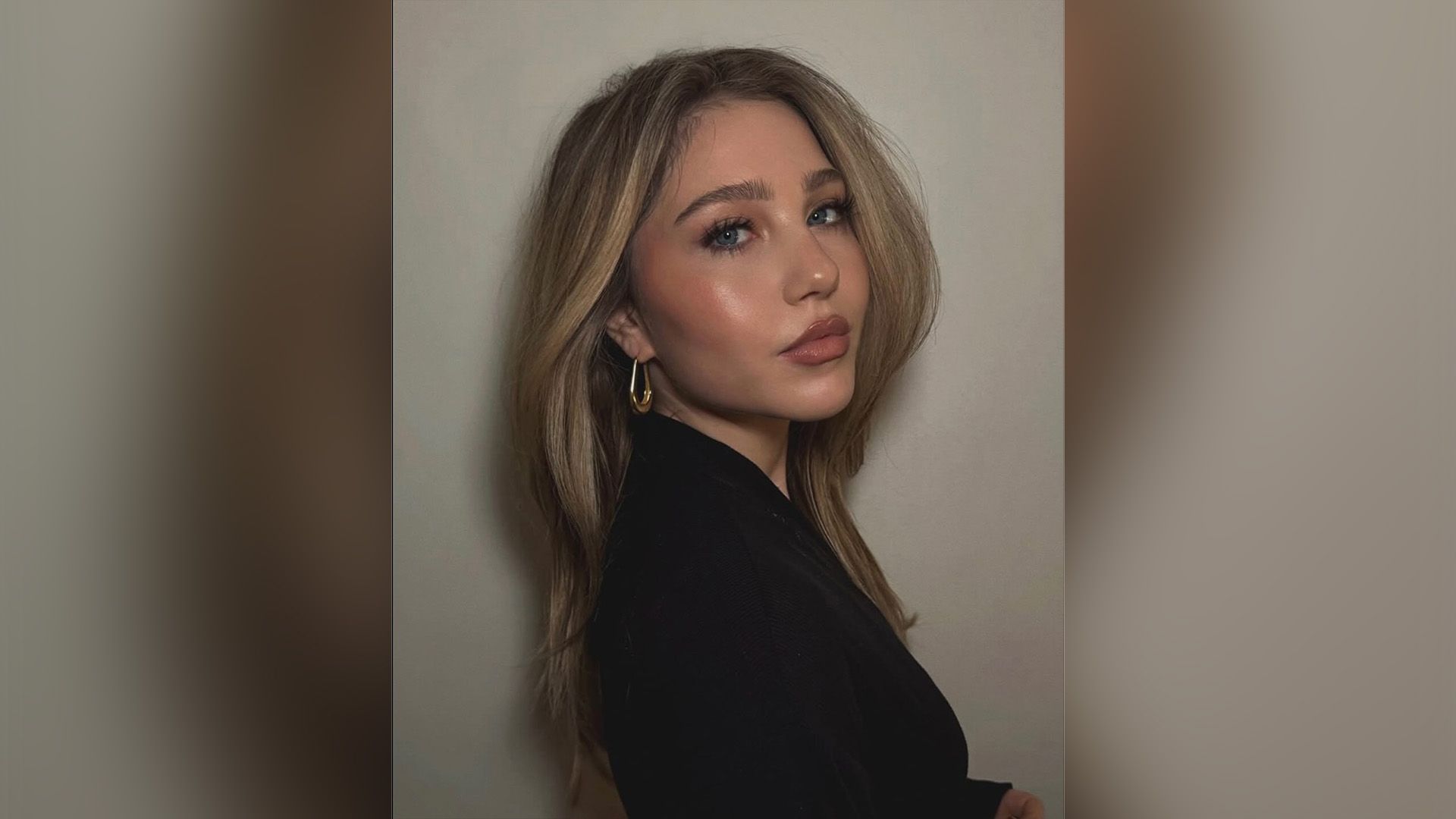 Ella Anderson in blazer nero in posa di tre quarti con un orecchino dorato